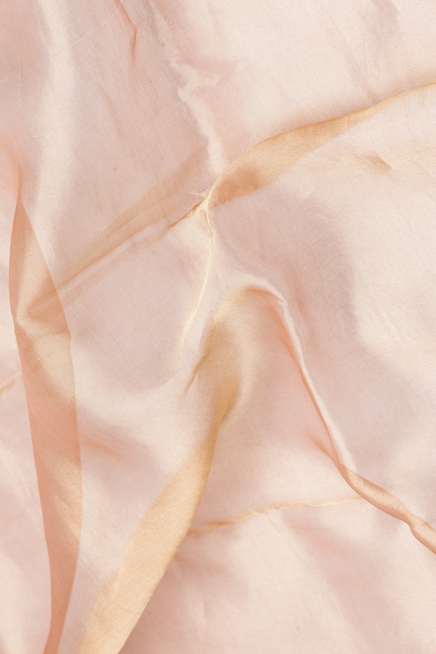 Close up of Rose Gold Dual Tone Organza Silk Saree with Plain Body and Zari Border.  displaying folds