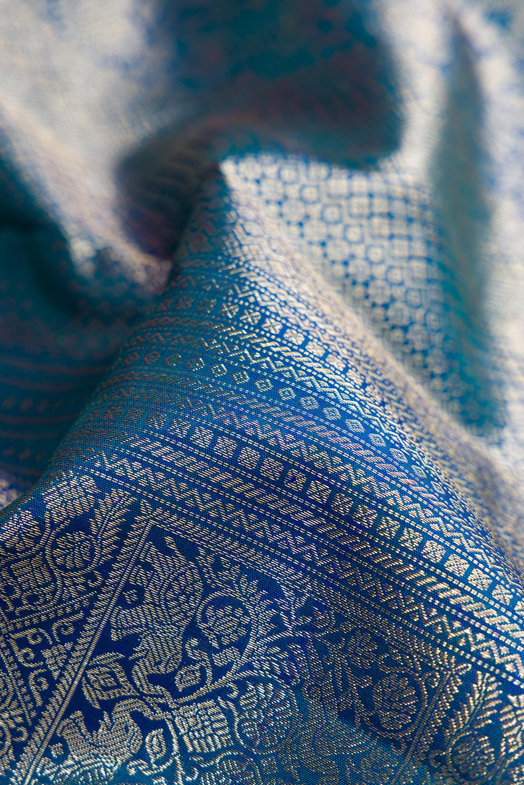 Close up of Peacock Blue Dual Tone Kanchipuram Silk Saree with Zari Brocade on the body and Zari Border.  displaying folds