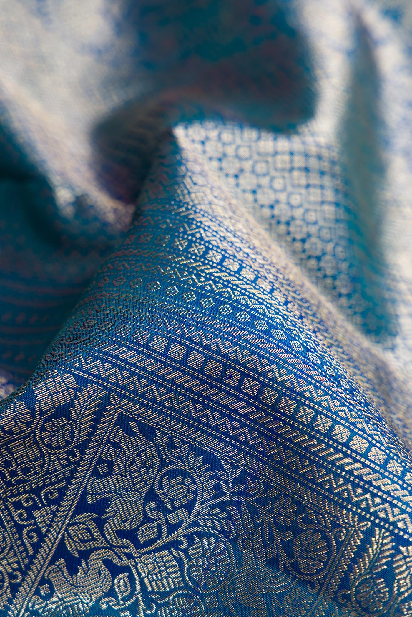 Close up of Peacock Blue Dual Tone Kanchipuram Silk Saree with Zari Brocade on the body and Zari Border.  displaying folds