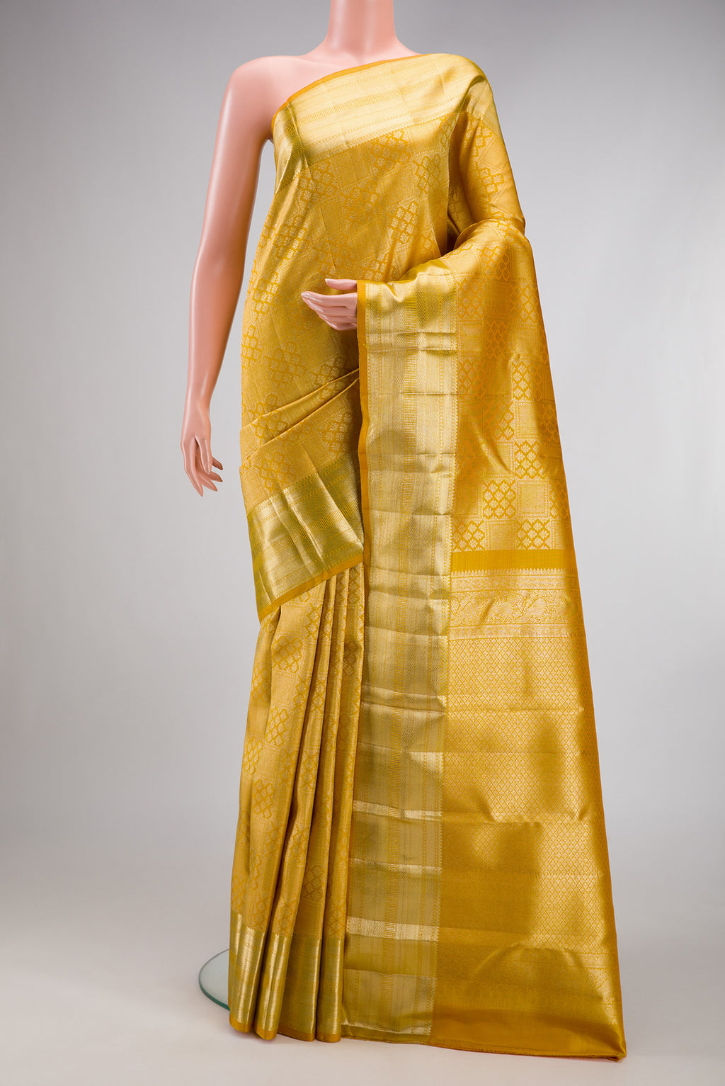 Mustard Kanchipuram Silk Saree with Zari Brocade on the body and Zari Border.  displayed on a mannequin