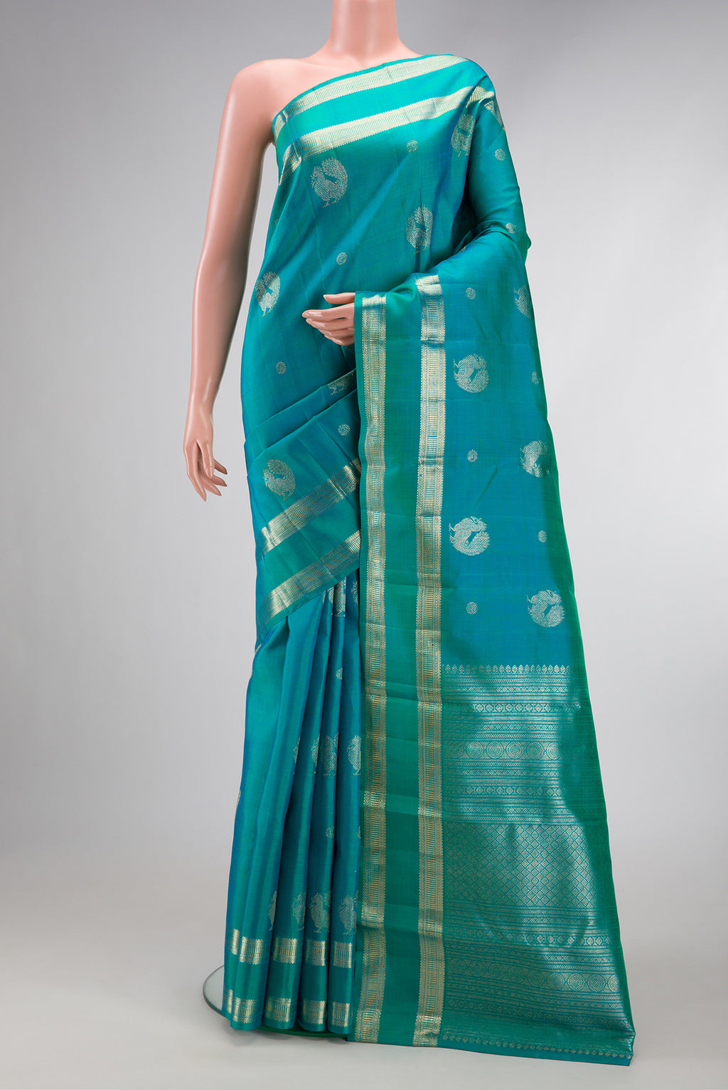 Peacock Blue Dual Tone Kanjivaram Silk Saree with Zari Butta on the body and Zari Border.  displayed on a mannequin