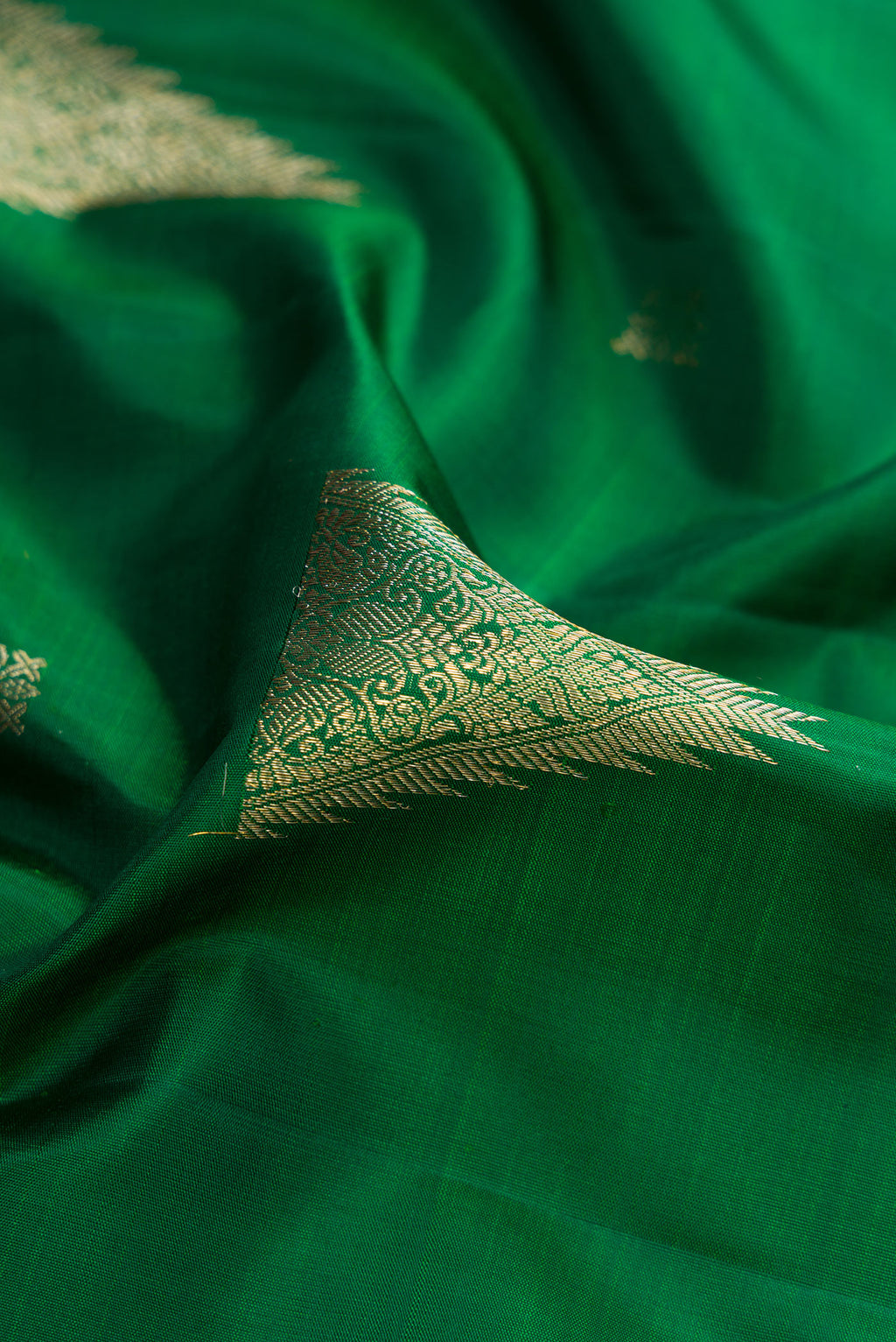 Close up of Bottle Green Kanjivaram Silk Saree with Zari Butta on the body and Zari Border.  displaying folds