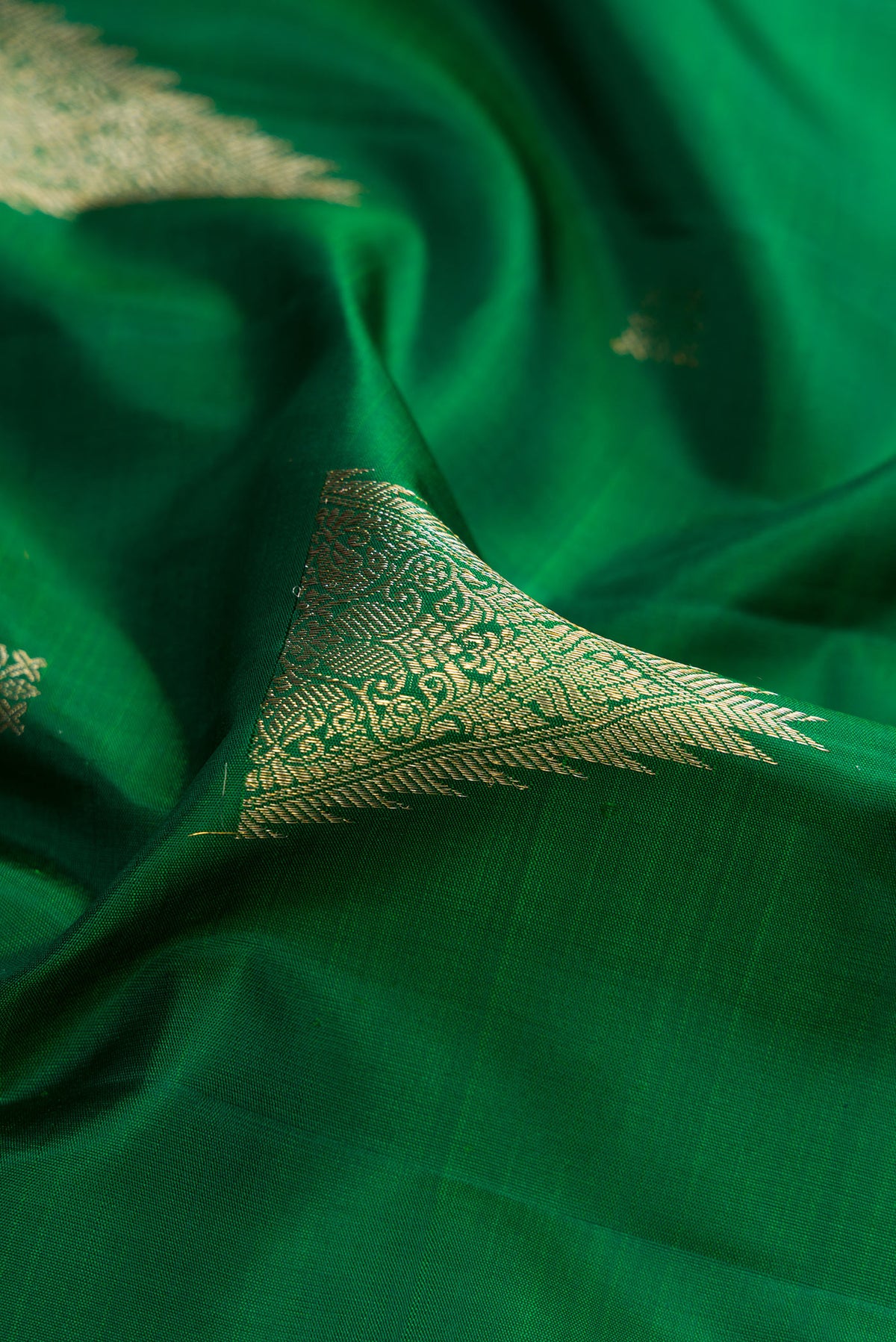 Close up of Bottle Green Kanjivaram Silk Saree with Zari Butta on the body and Zari Border.  displaying folds