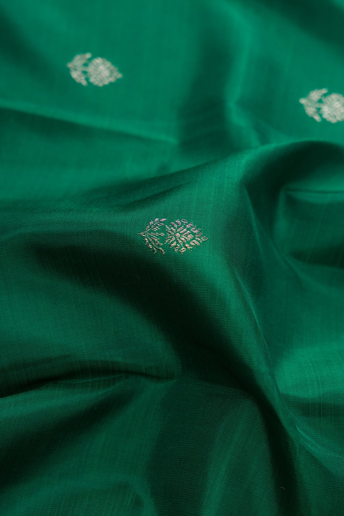 Close up of Pure Silk Bottle Green Kanjivaram Saree with Zari Butta on the body and Fancy Border.  displaying folds