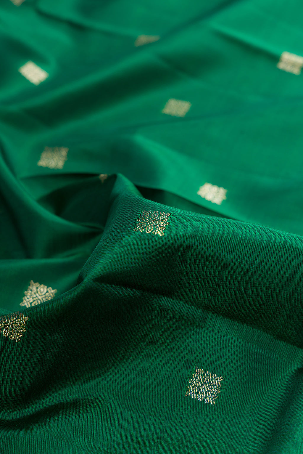 Close up of Pure Silk Bottle Green Kanjivaram Saree with Zari Butta on the body and Zari Border.  displaying folds