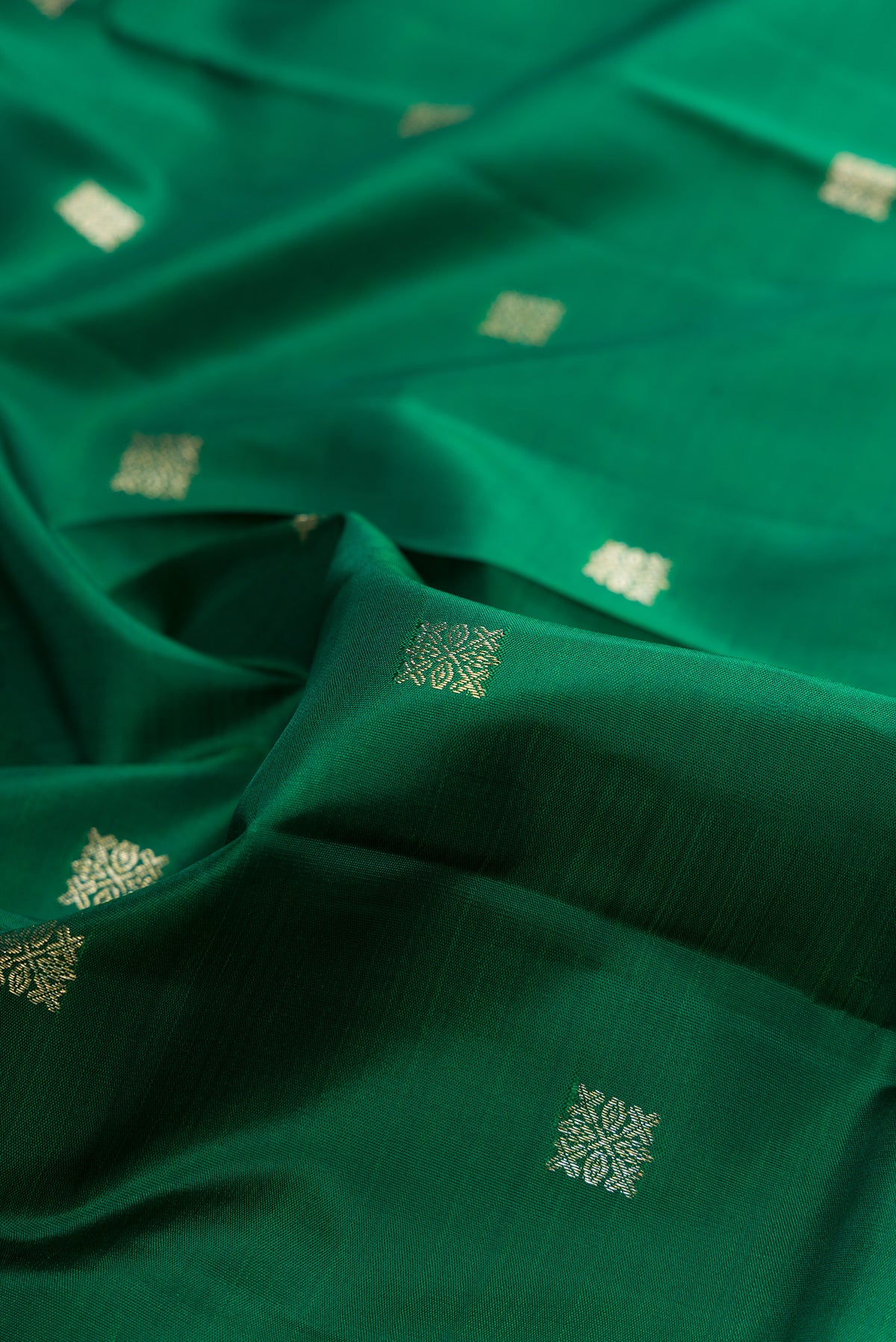 Close up of Pure Silk Bottle Green Kanjivaram Saree with Zari Butta on the body and Zari Border.  displaying folds