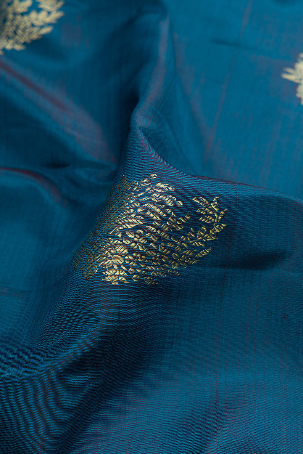 Close up of Peacock Blue Kanjivaram Silk Saree with Zari Butta on the body and Zari Border.  displaying folds
