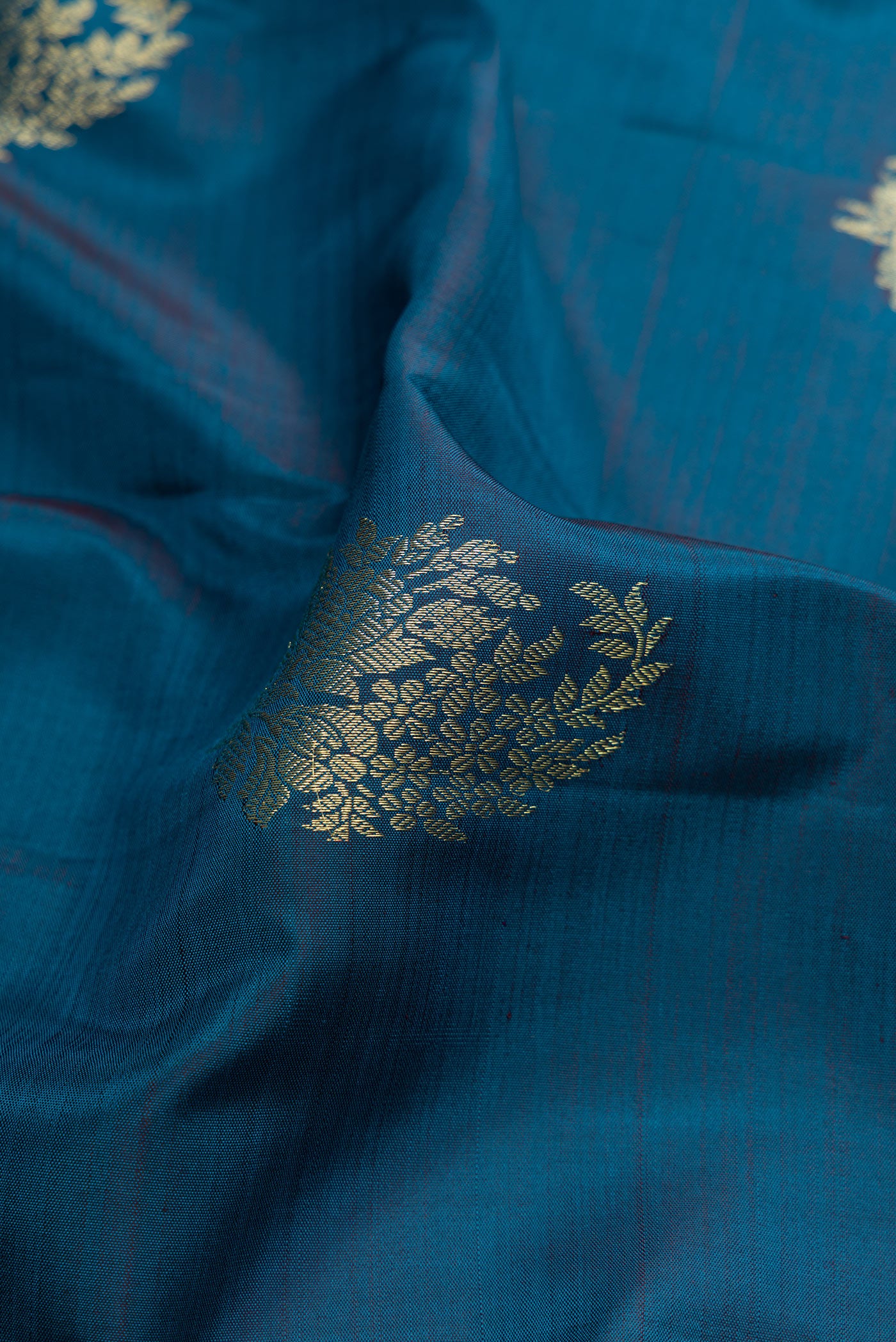 Close up of Peacock Blue Kanjivaram Silk Saree with Zari Butta on the body and Zari Border.  displaying folds