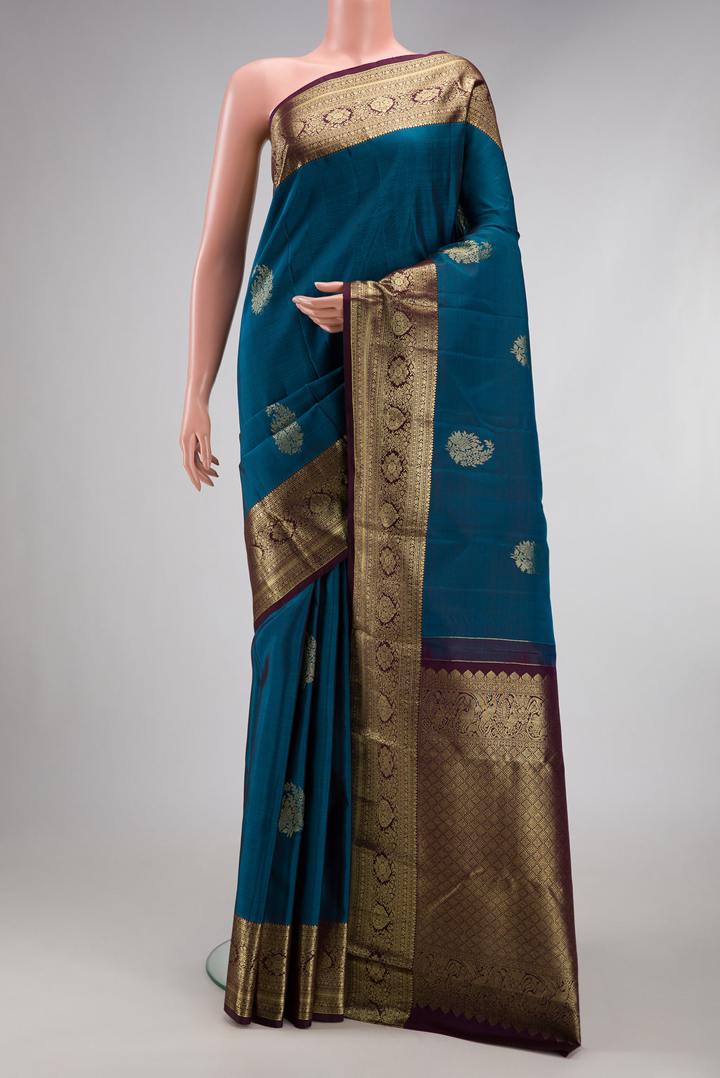 Peacock Blue Kanjivaram Silk Saree with Zari Butta on the body and Zari Border.  displayed on a mannequin