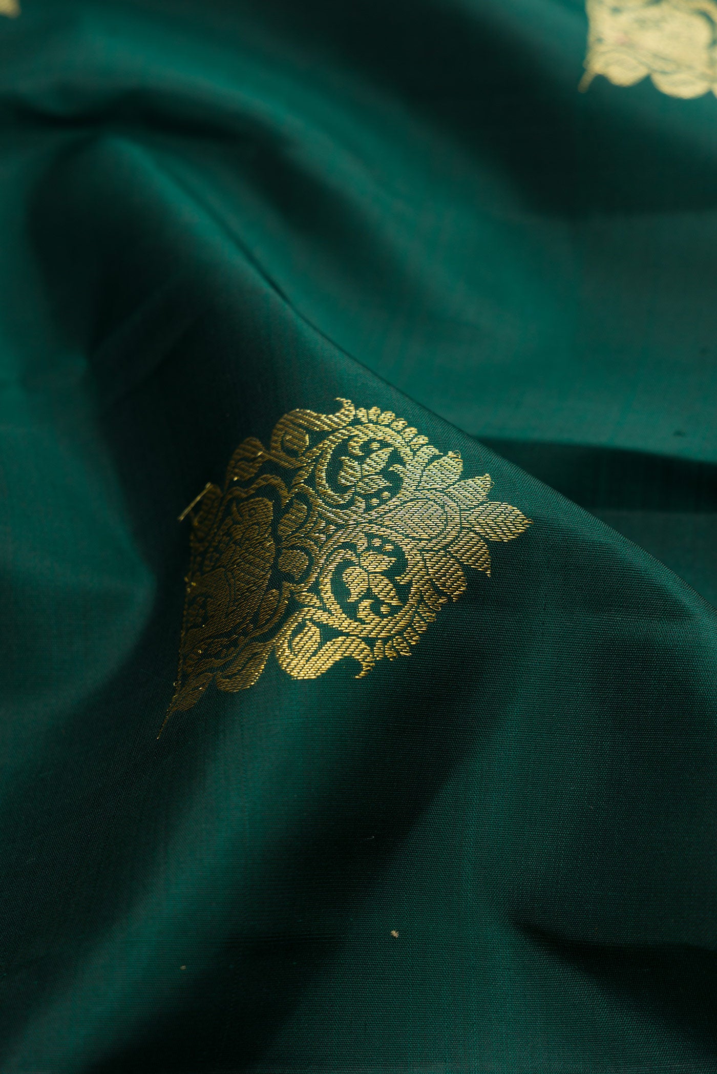 Close up of Bottle Green Kanjivaram Silk Saree with Zari Butta on the body and Zari Border.  displaying folds