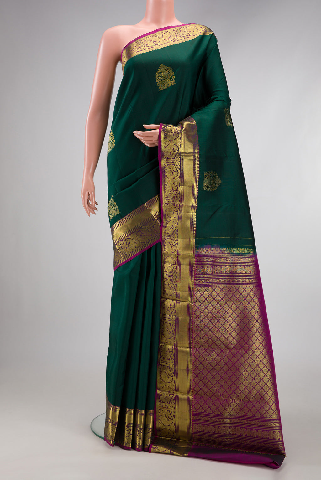 Bottle Green Kanjivaram Silk Saree with Zari Butta on the body and Zari Border.  displayed on a mannequin