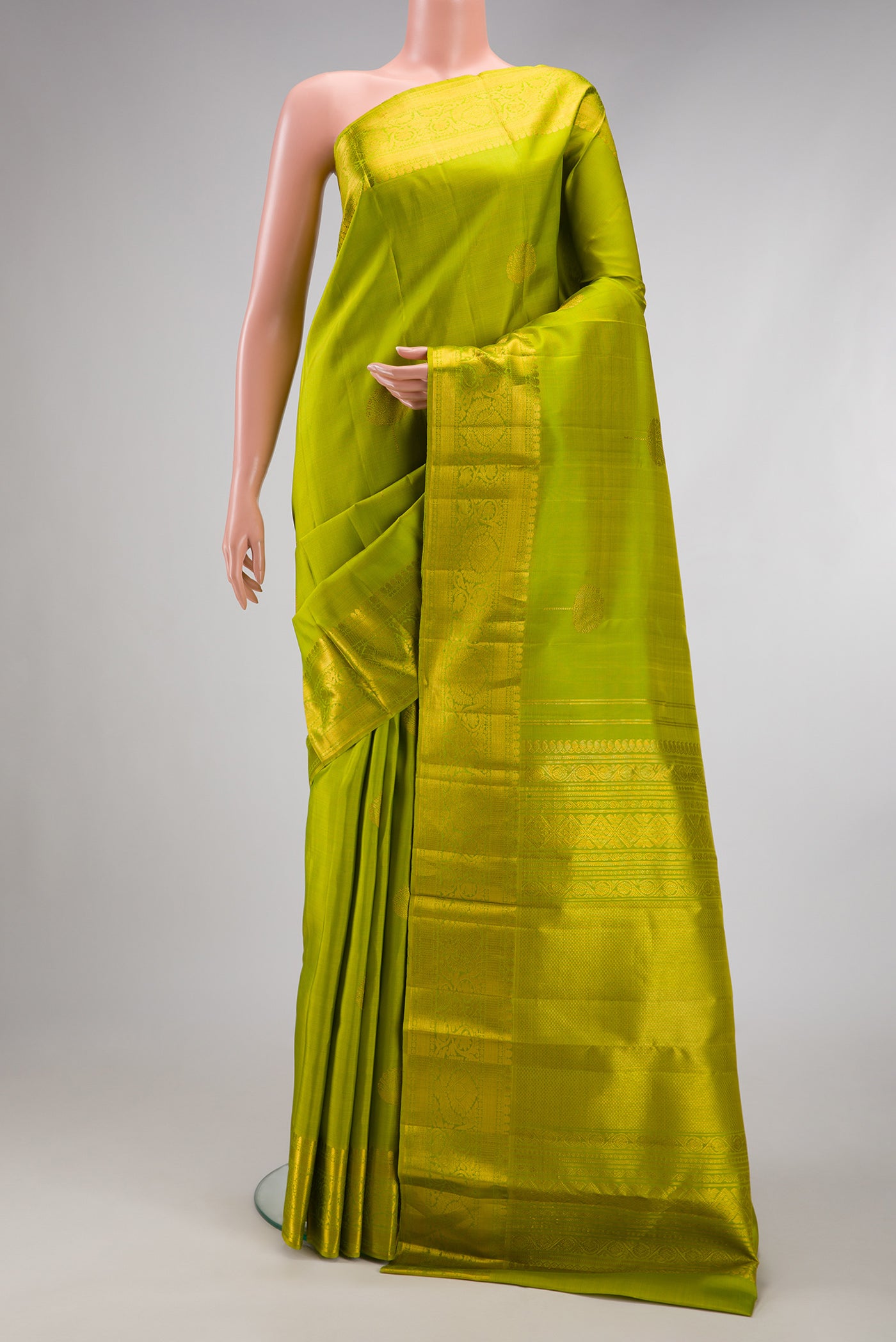 Parrot Green Kanjivaram Silk Saree with Zari Butta on the body and Zari Border.  displayed on a mannequin