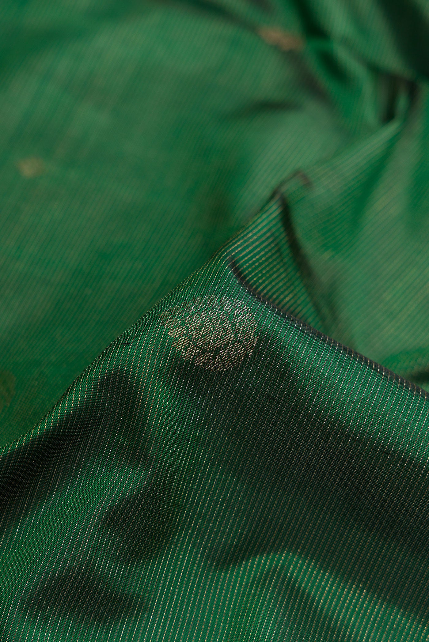 Close up of Green Soft Silk Saree with Zari Butta on the body and Zari Border.  displaying folds