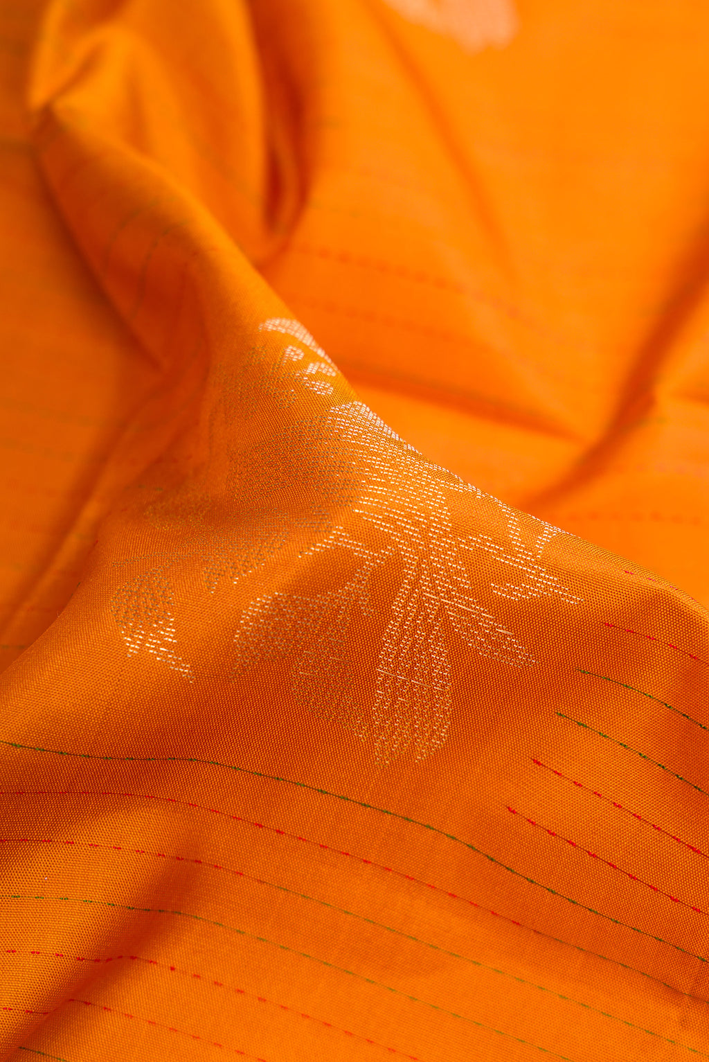 Close up of Orange Soft Silk Saree with Zari Butta on the body and Fancy Border.  displaying folds