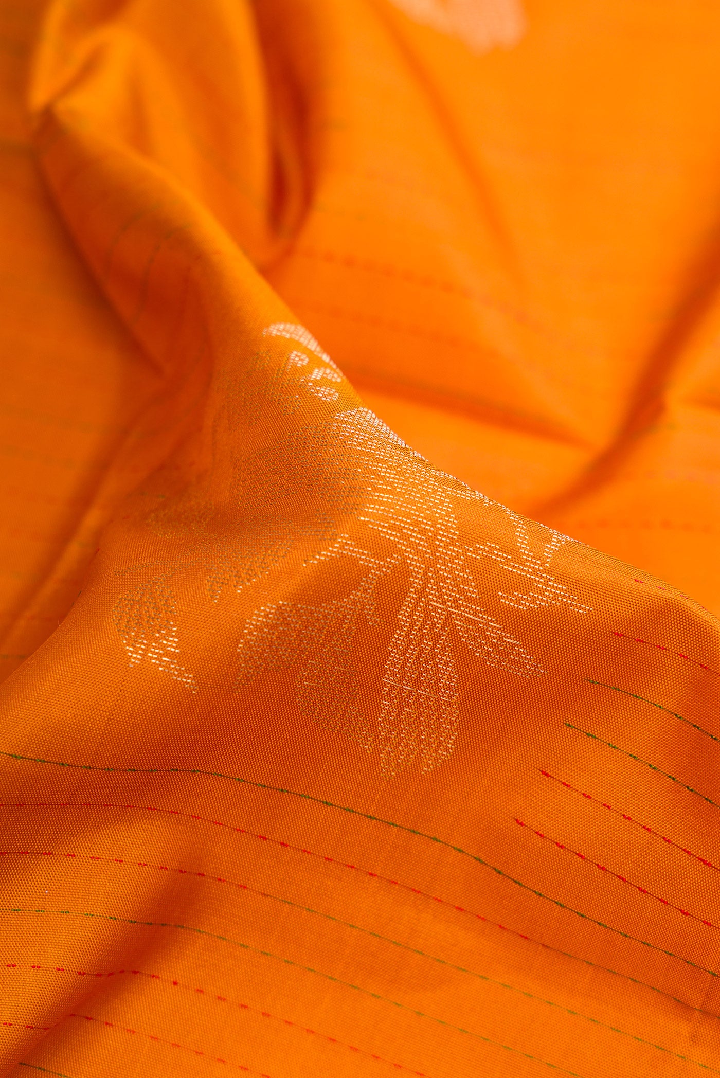 Close up of Orange Soft Silk Saree with Zari Butta on the body and Fancy Border.  displaying folds