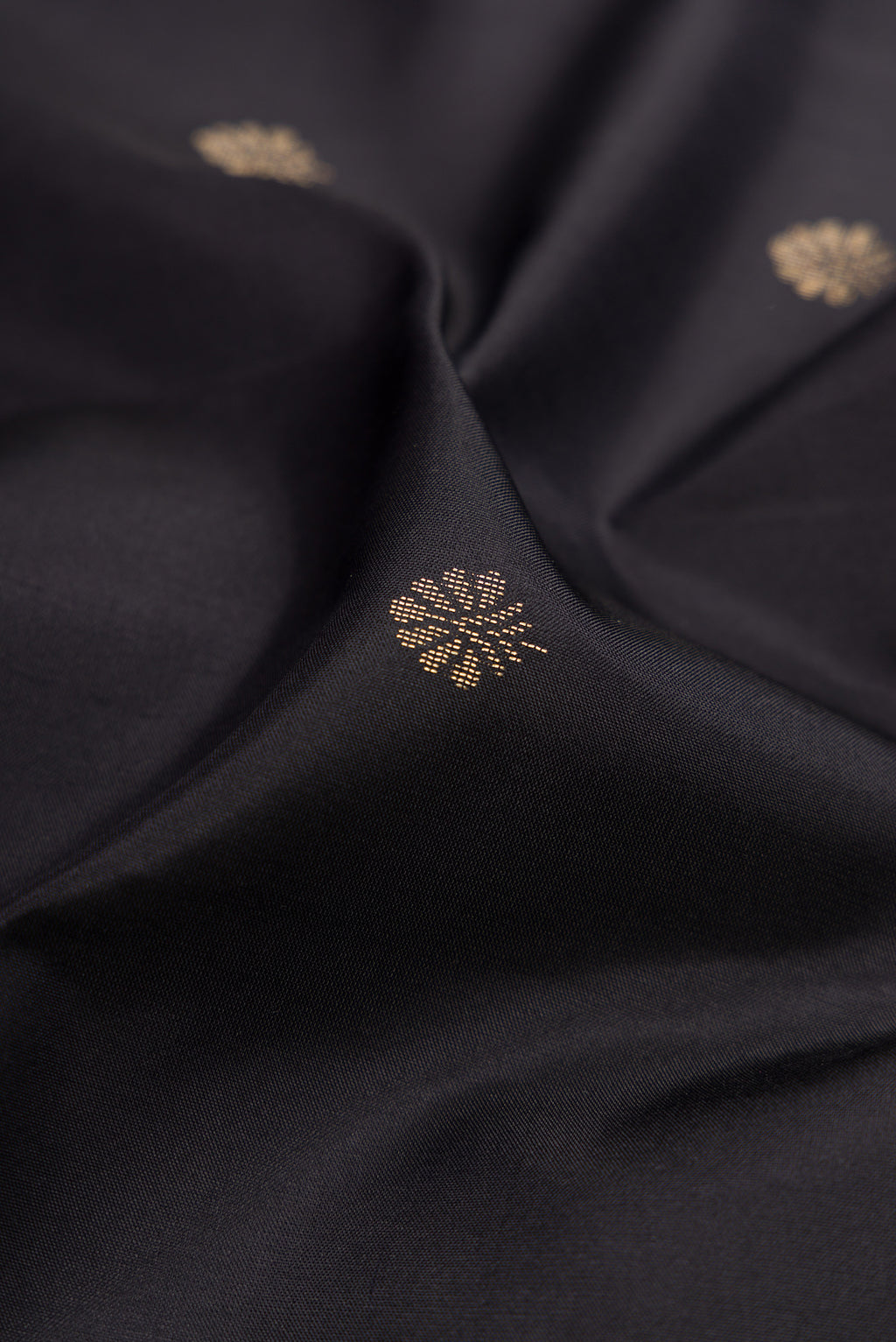 Close up of Black Soft Silk Saree with Zari Butta on the body and Fancy Border.  displaying folds