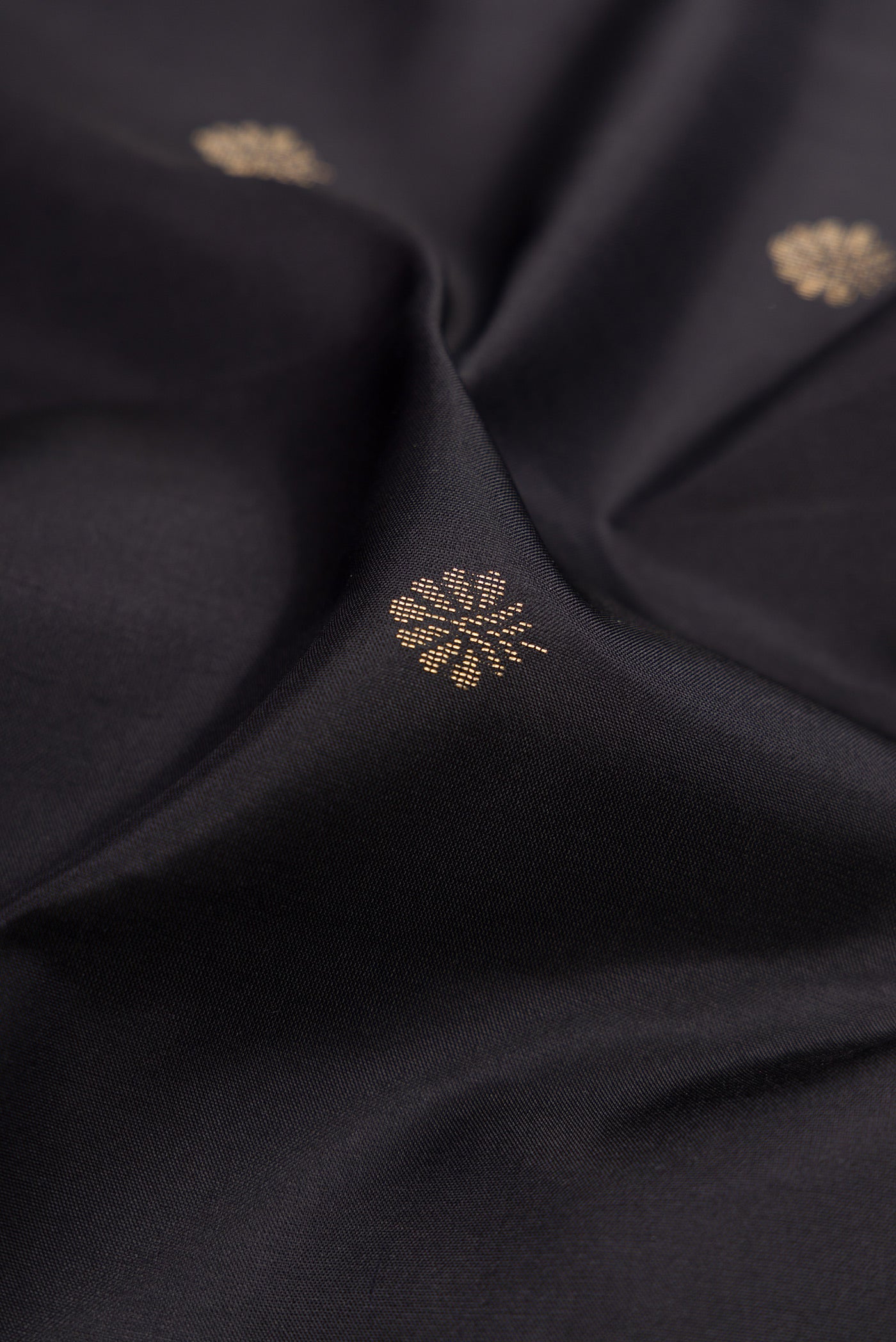 Close up of Black Soft Silk Saree with Zari Butta on the body and Fancy Border.  displaying folds