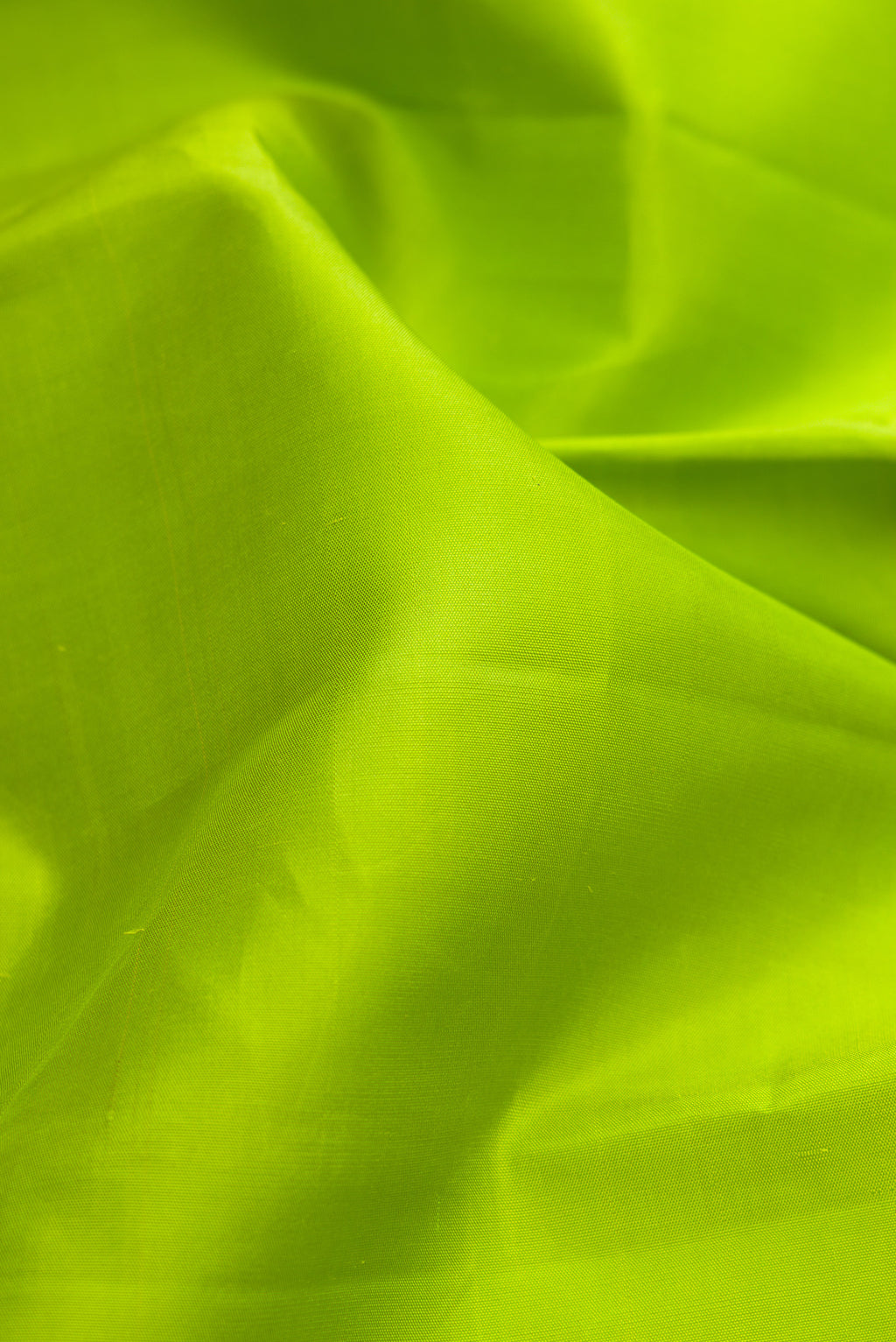 Close up of Parrot Green Kanjivaram Silk Saree with Plain Body and Thread Border.  displaying folds