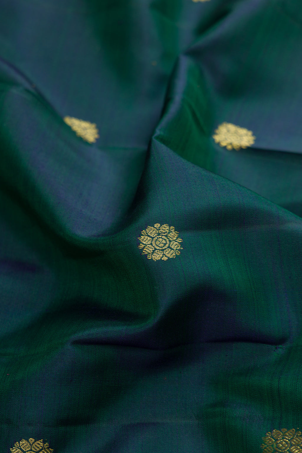 Close up of Bottle Green Kanchipuram Silk Saree with Zari Butta on the body and Zari Border.  displaying folds