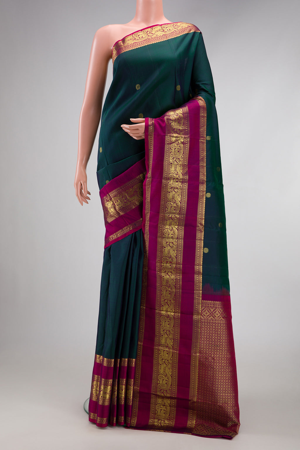 Bottle Green Kanchipuram Silk Saree with Zari Butta on the body and Zari Border.  displayed on a mannequin