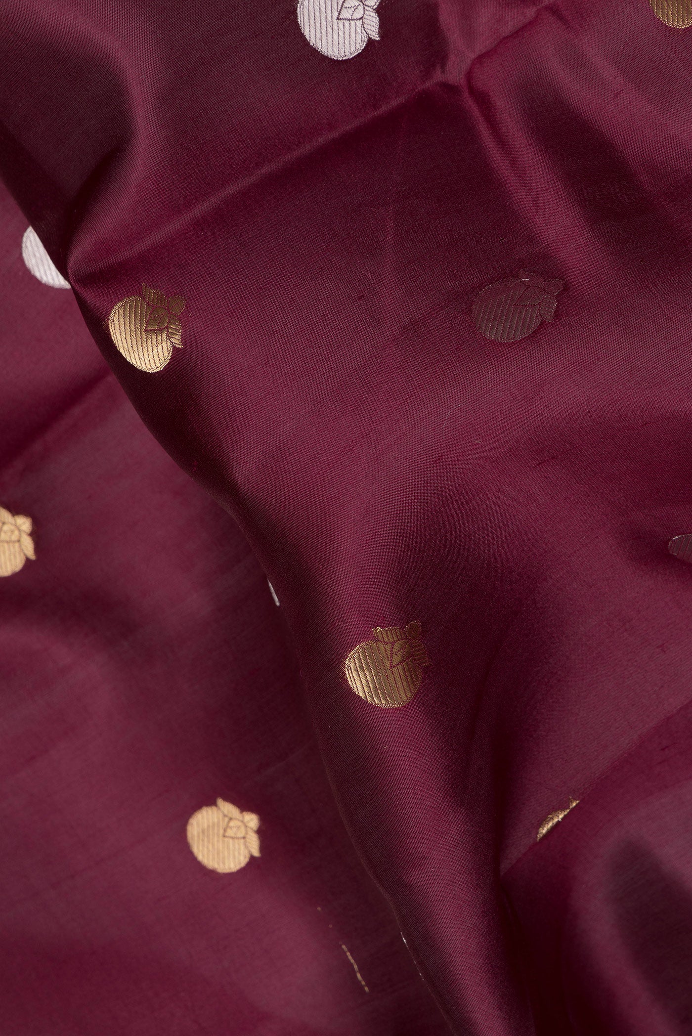 Close up of Maroon Tussar Silk Saree with Zari Butta on the body and Zari Border.  displaying folds