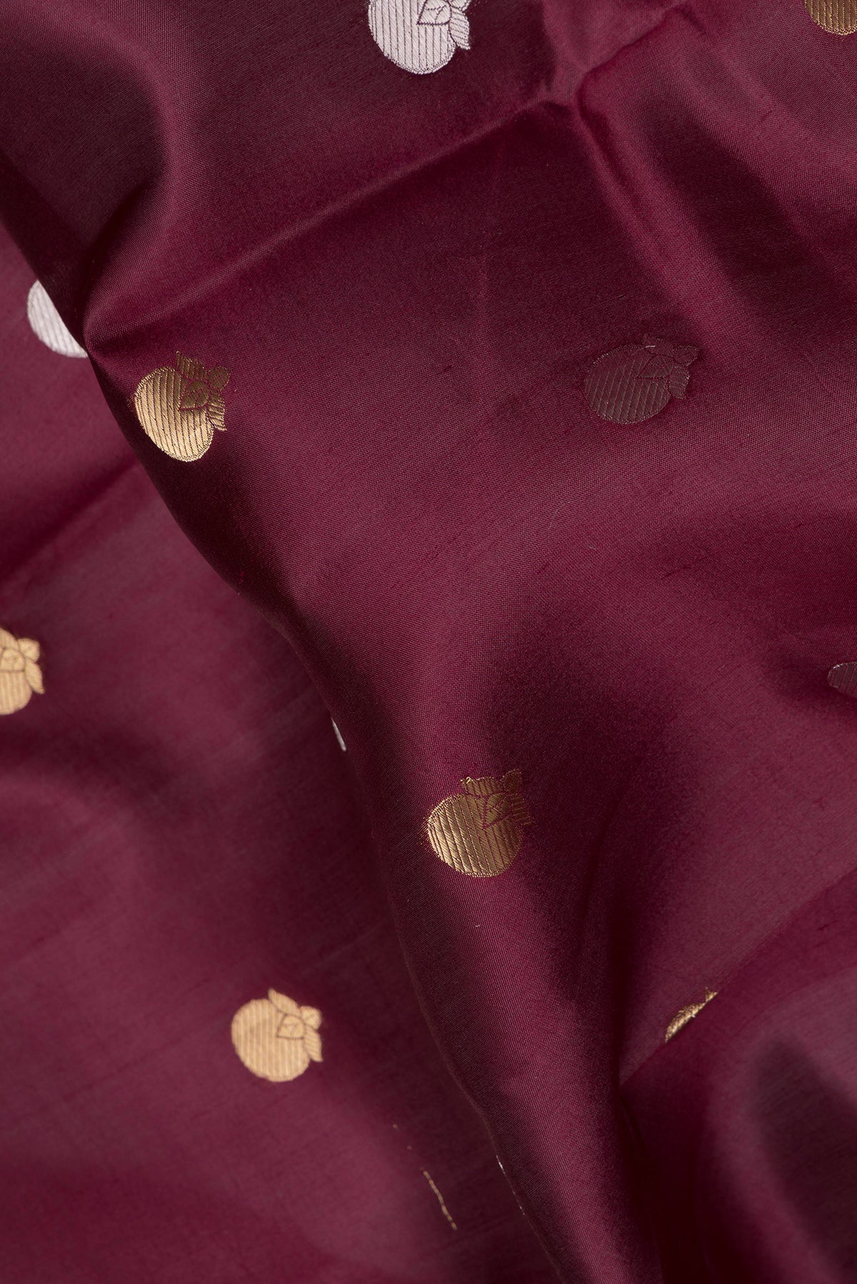 Close up of Maroon Tussar Silk Saree with Zari Butta on the body and Zari Border.  displaying folds