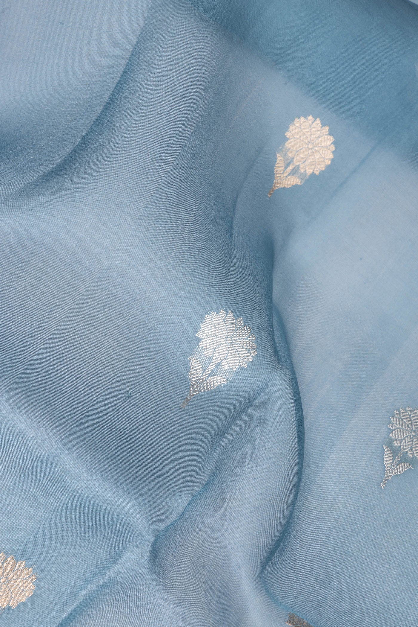 Close up of Blue Grey Organza Silk Saree with Zari Butta on the body and Zari Border.  displaying folds