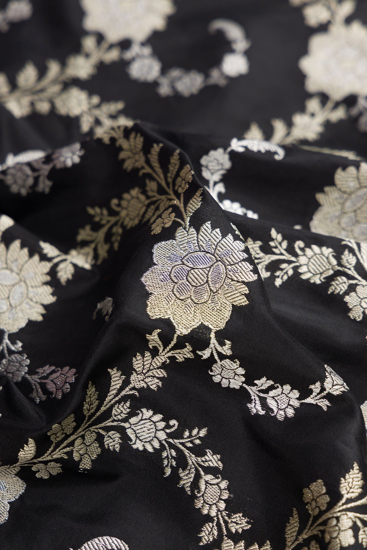 Close up of Black Dual Tone Banarasi Silk Saree with Zari Butta on the body and Zari Border.  displaying folds