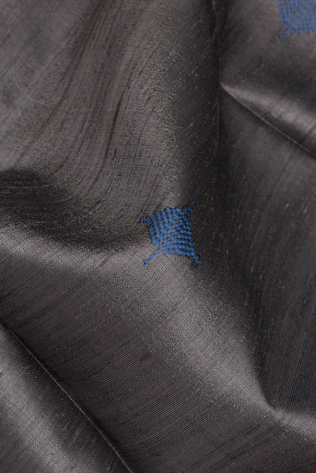Close up of Grey Tussar Silk Saree with Thread Butta on the body and Zari Border.  displaying folds