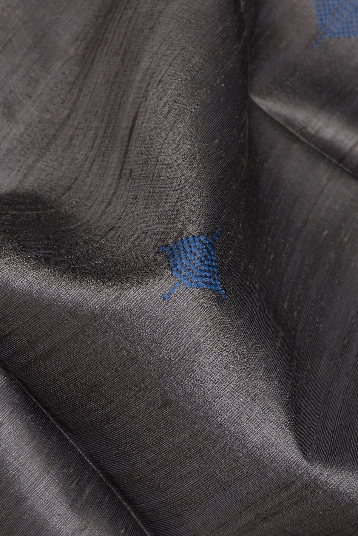 Close up of Grey Tussar Silk Saree with Thread Butta on the body and Zari Border.  displaying folds