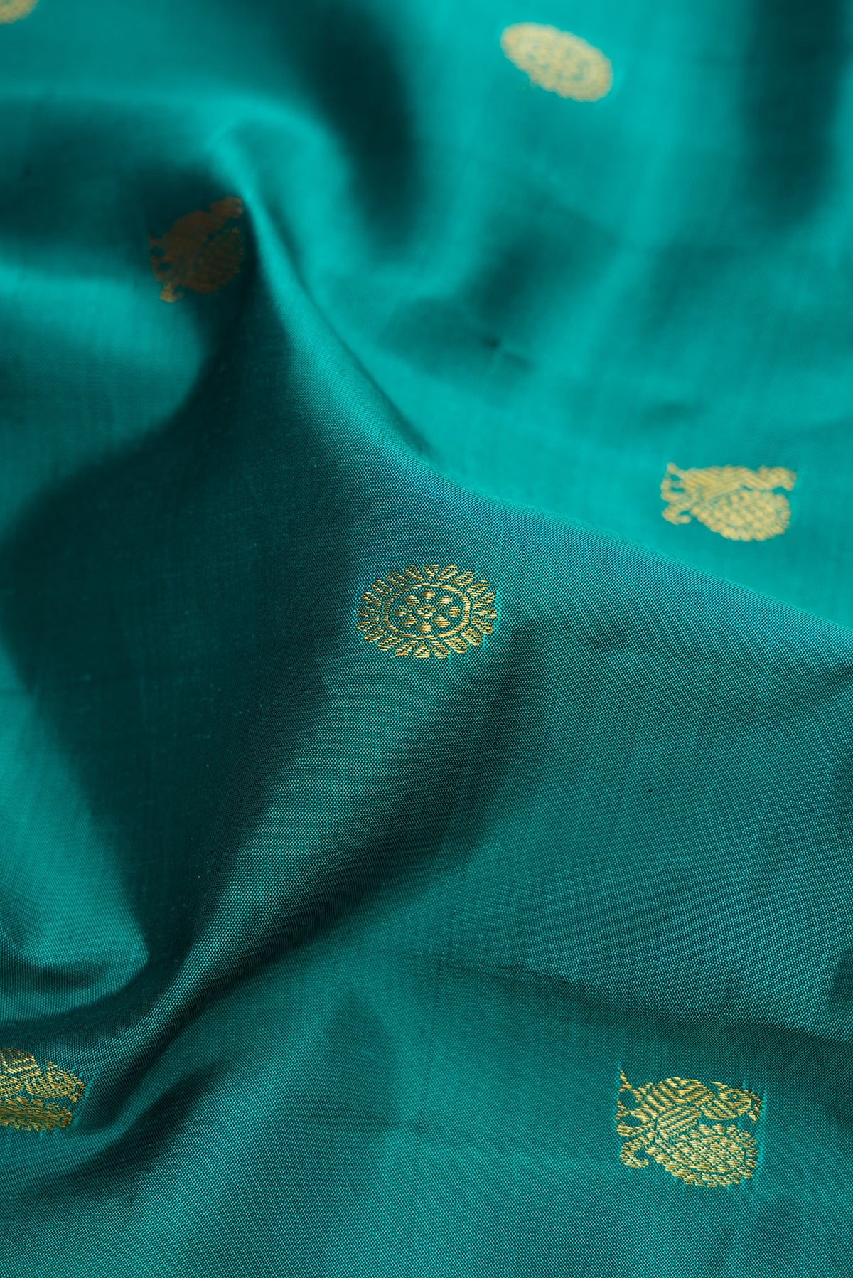 Close up of Teal Kanjivaram Silk Saree with Zari Butta on the body and Zari Border.  displaying folds