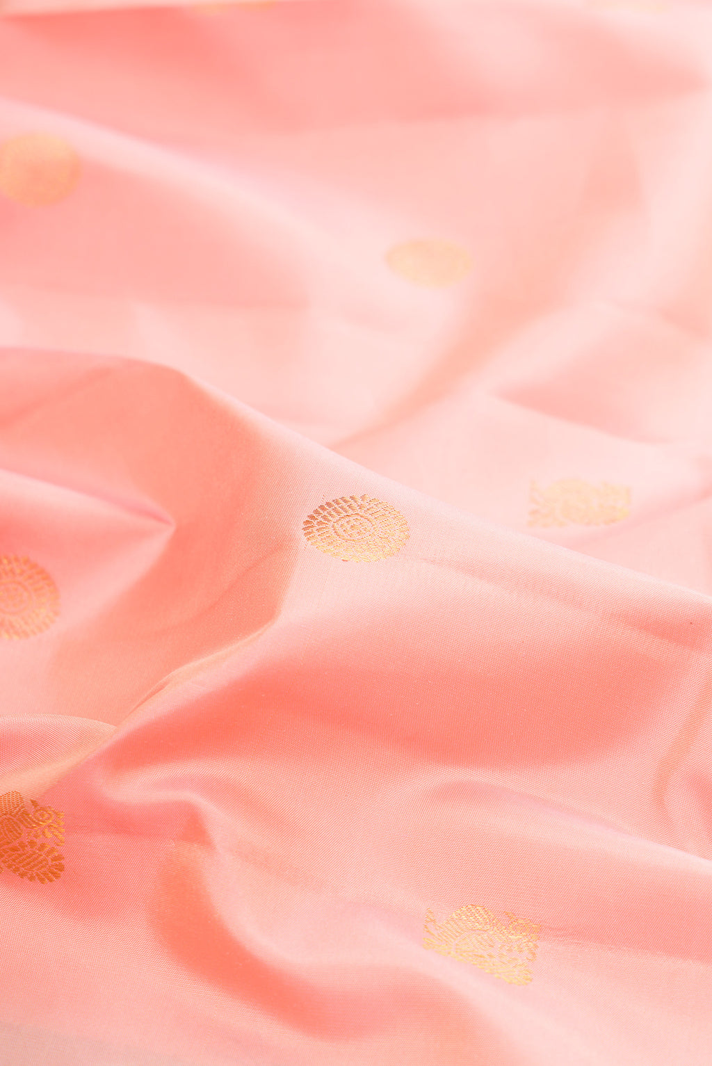 Close up of Pure Silk Peach Kanjivaram Saree with Zari Butta on the body and Zari Border.  displaying folds