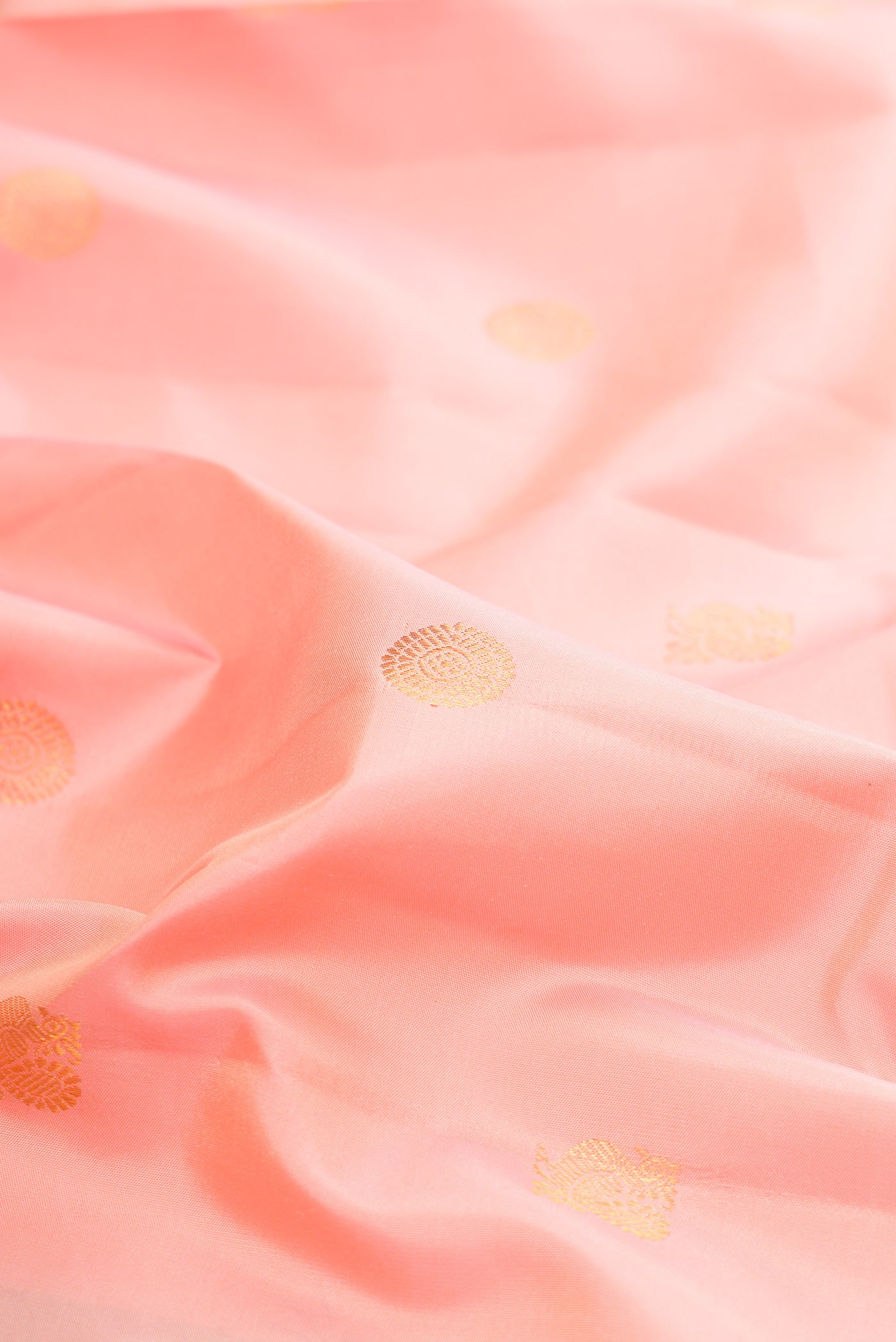 Close up of Pure Silk Peach Kanjivaram Saree with Zari Butta on the body and Zari Border.  displaying folds