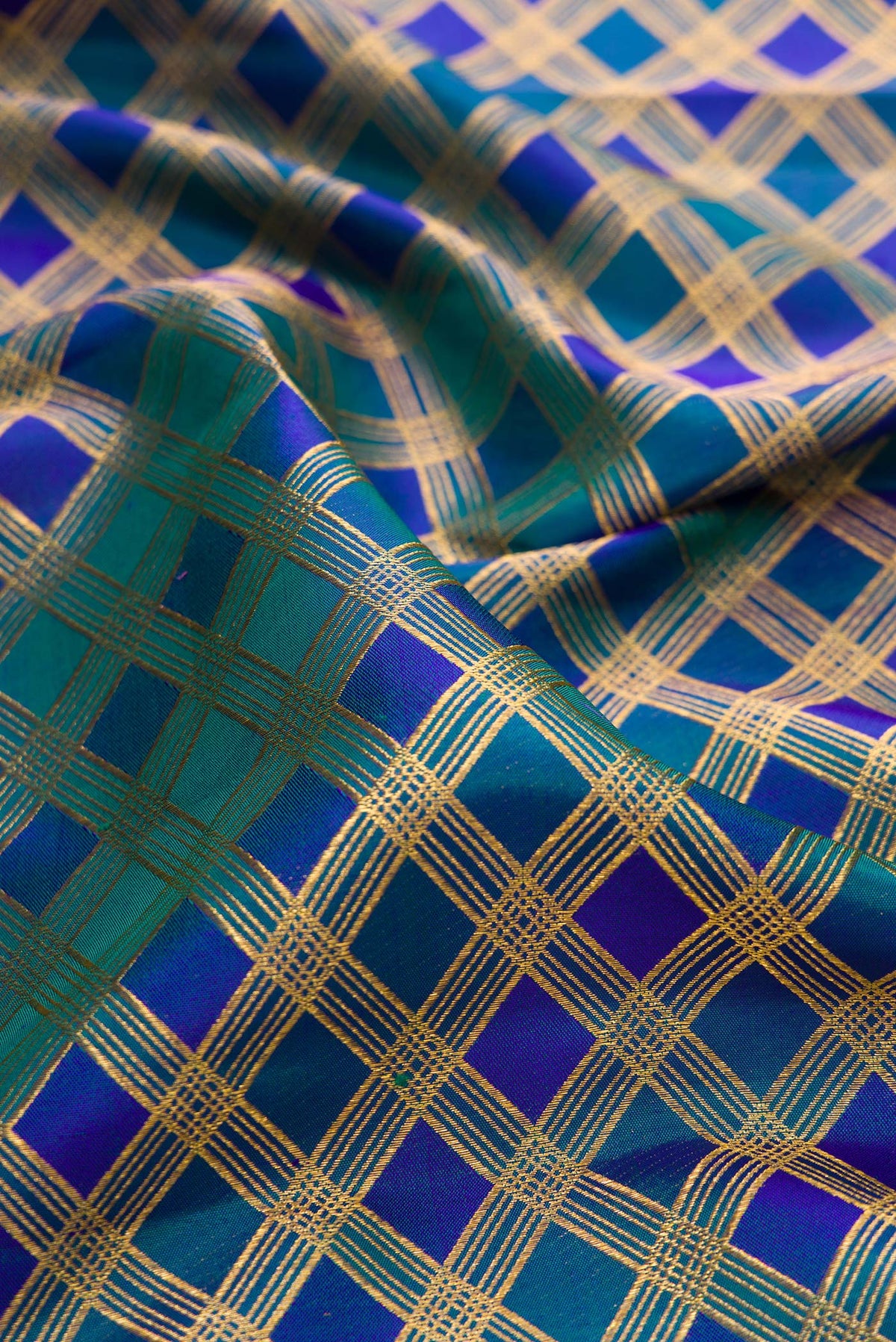 Close up of Pure Silk Peacock Blue Dual Tone Kanjivaram Saree with Checked design on the body and Zari Border.  displaying folds