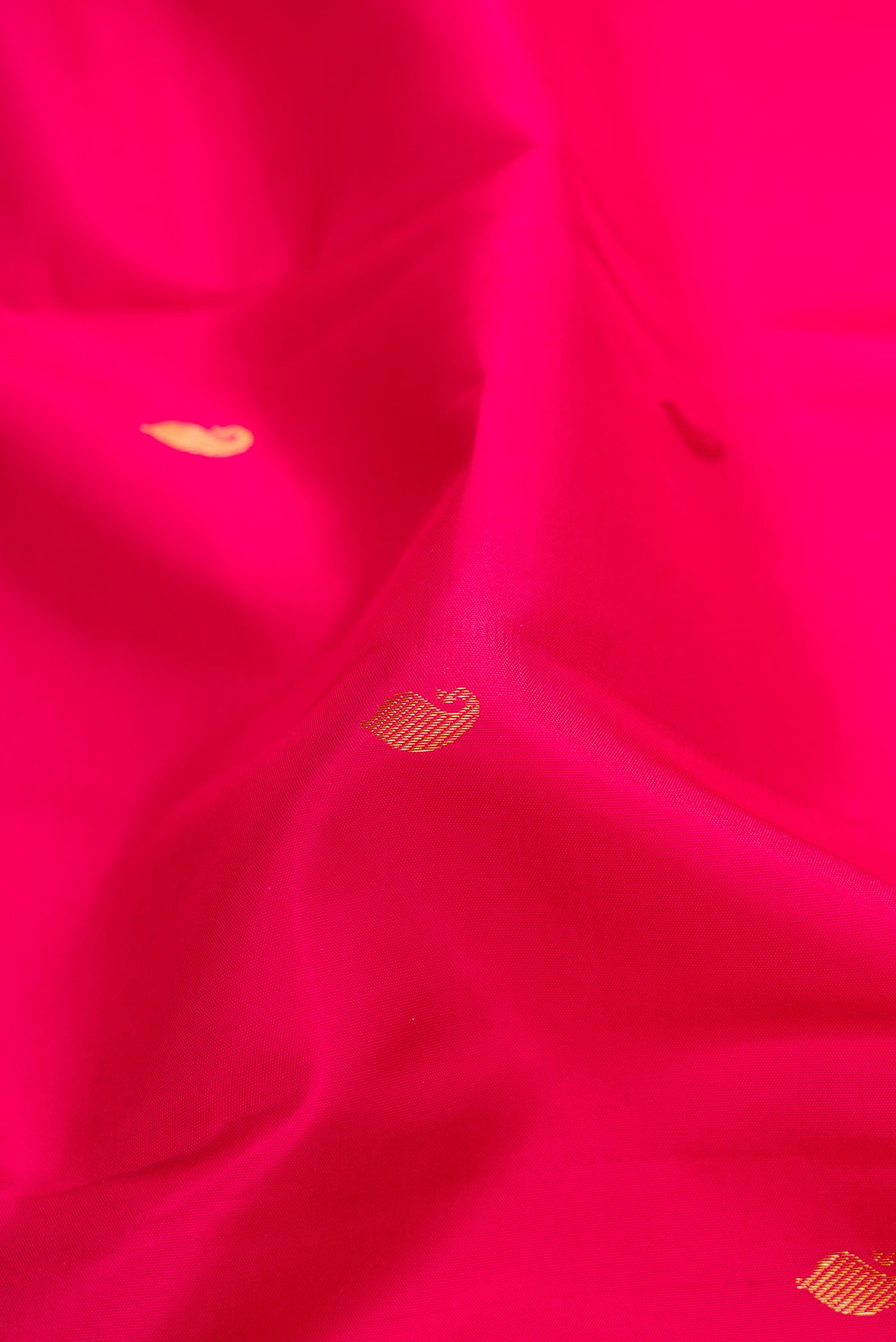 Close up of Dark Pink Kanchipuram Silk Saree with Zari Butta on the body and Zari Border.  displaying folds