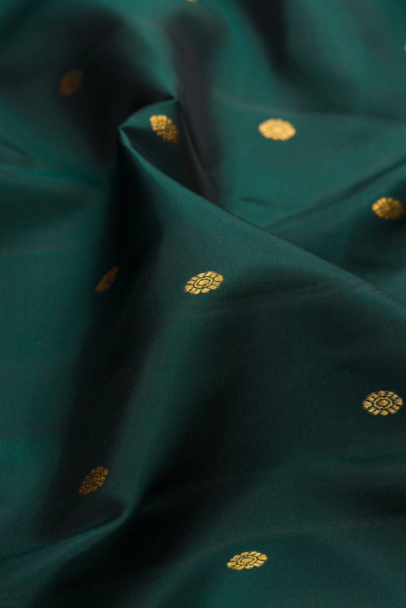 Close up of Bottle Green Kanchipuram Silk Saree with Zari Butta on the body and Fancy Border.  displaying folds
