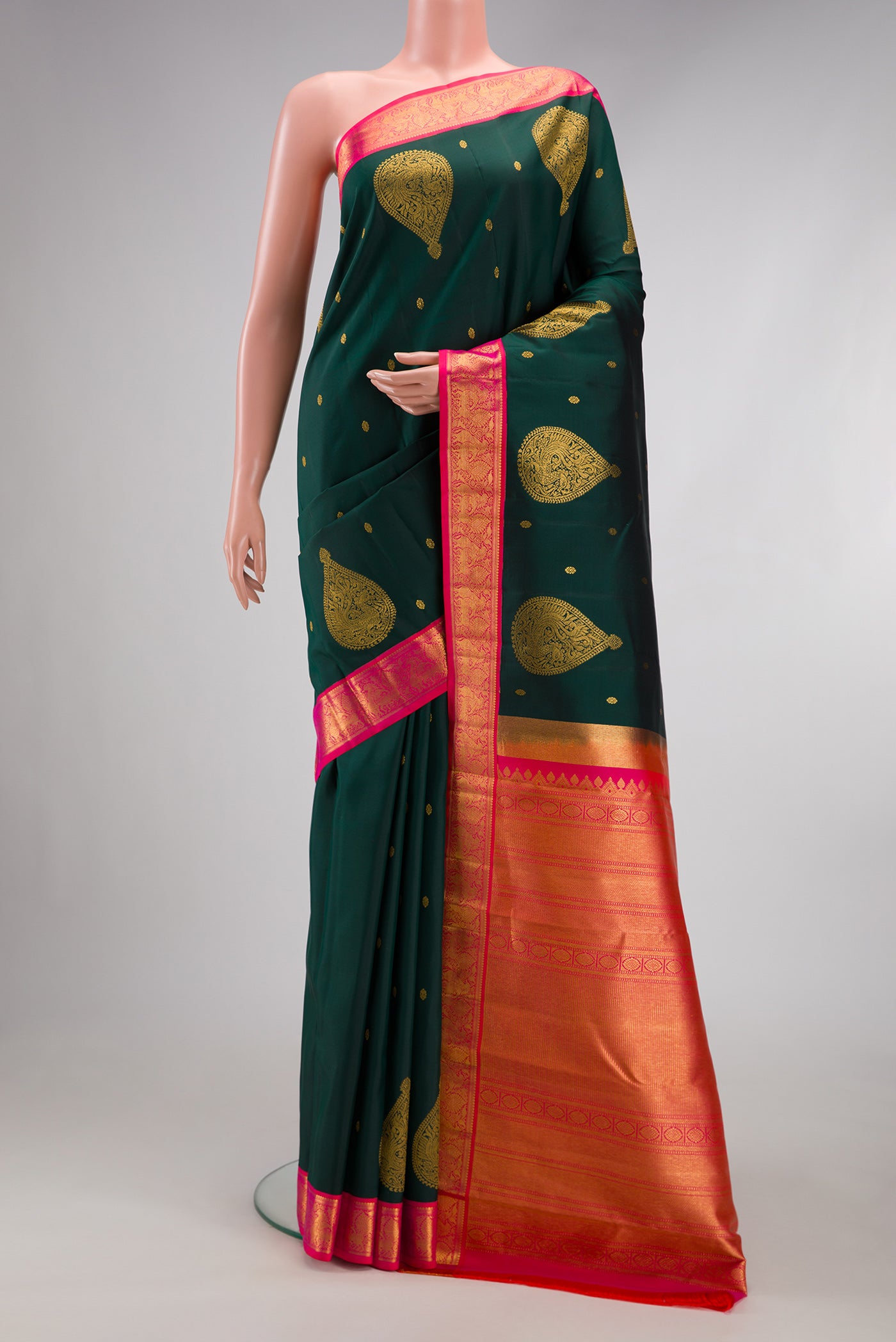 Bottle Green Kanchipuram Silk Saree with Zari Butta on the body and Fancy Border.  displayed on a mannequin
