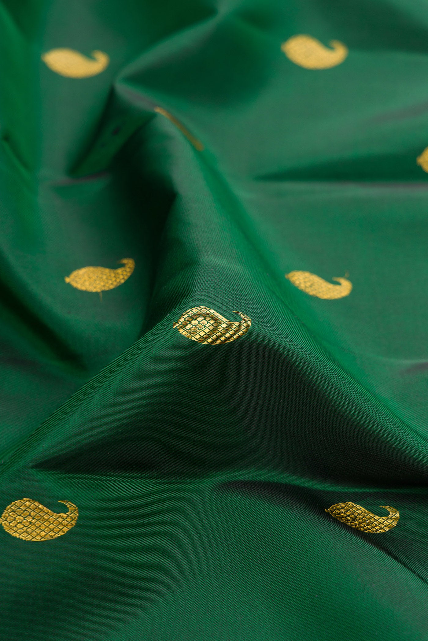 Close up of Bottle Green Kanchipuram Silk Saree with Zari Butta on the body and Zari Border.  displaying folds