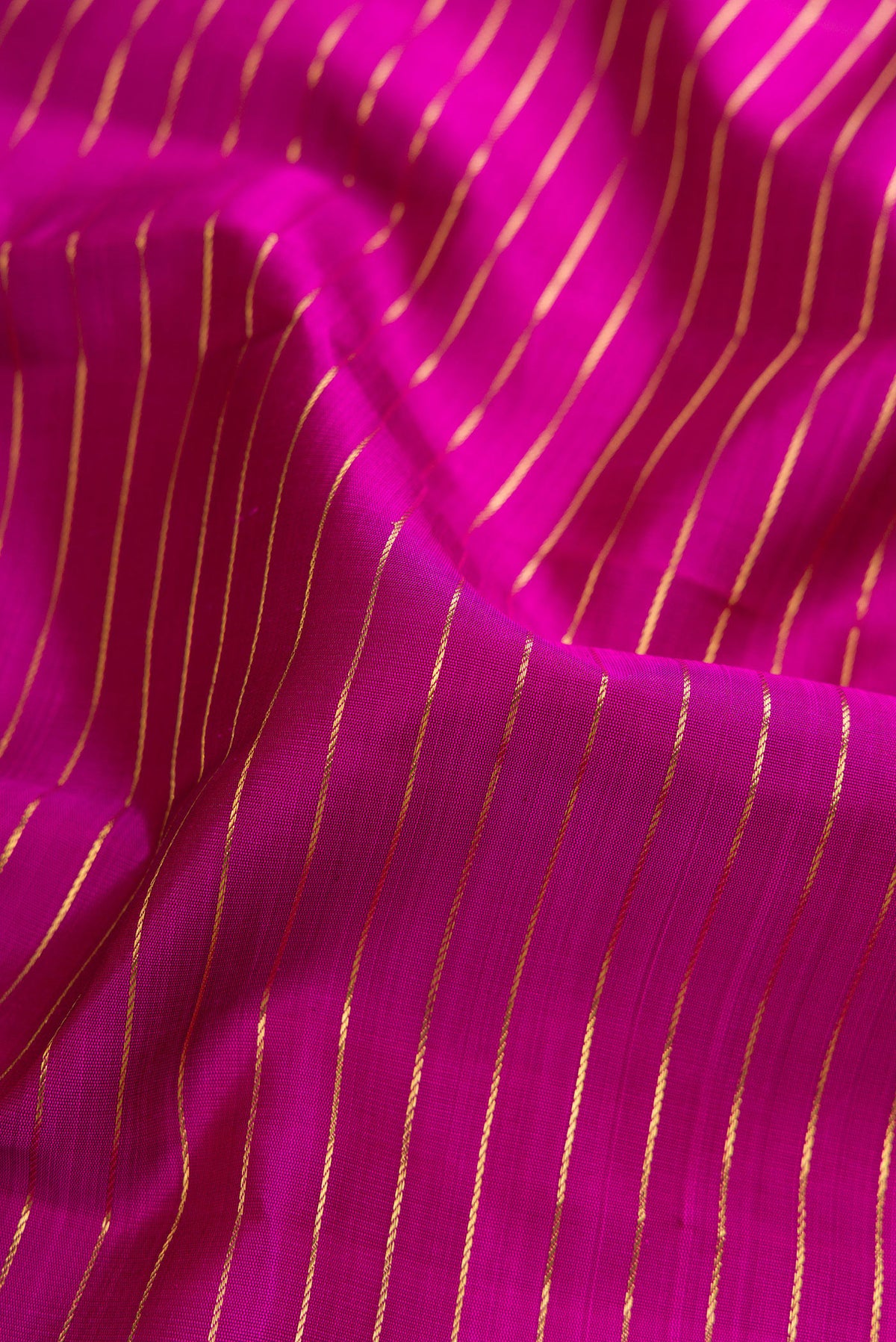 Close up of Pure Silk Pure Zari Magenta Dual Tone Kanjivaram Saree with Stripes on the body and Zari Border.  displaying folds