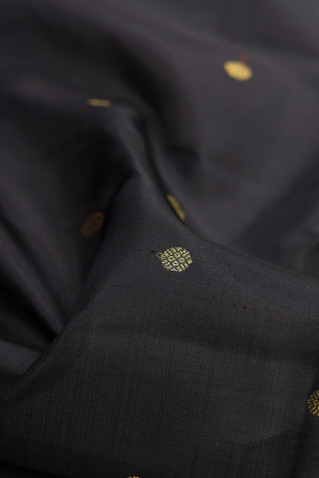 Close up of Pure Silk Pure Zari Black Dual Tone Kanchipuram Saree with Zari Butta on the body and Zari Border.  displaying folds
