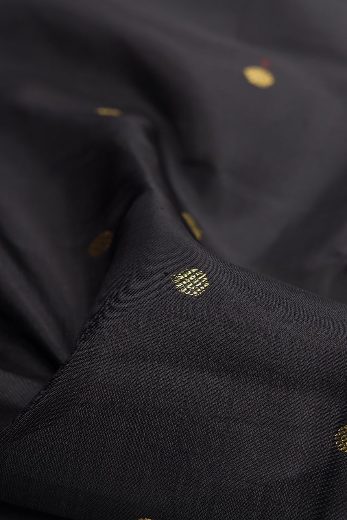 Close up of Pure Silk Pure Zari Black Dual Tone Kanchipuram Saree with Zari Butta on the body and Zari Border.  displaying folds