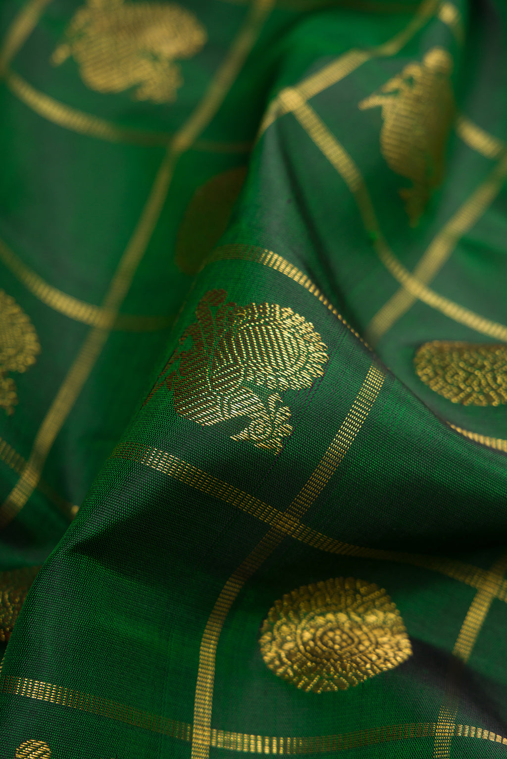 Close up of Pure Silk Pure Zari Bottle Green Kanjivaram Saree with Checked design on the body and Zari And Thread Border.  displaying folds