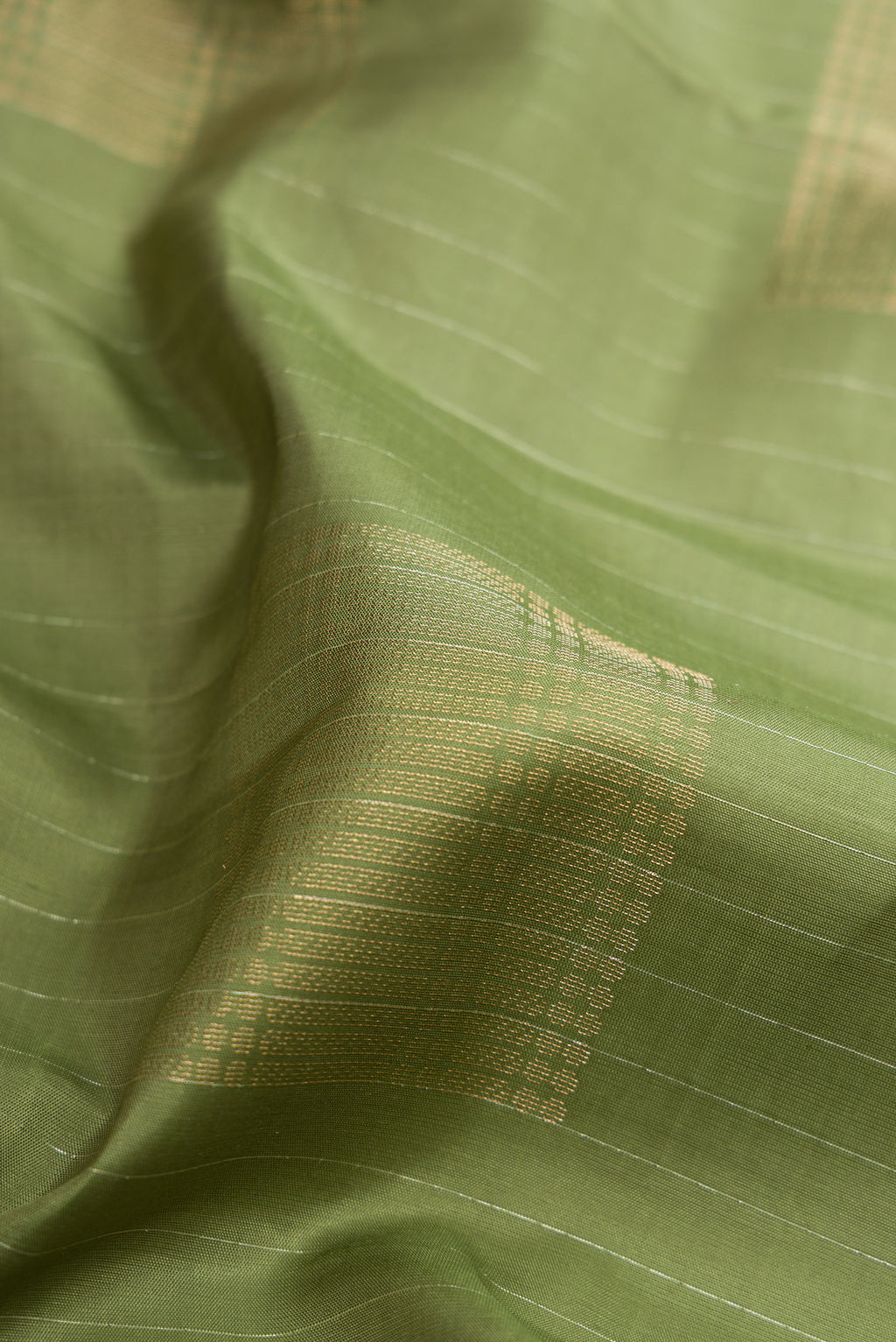 Close up of Sage Green Soft Silk Saree with Zari Butta on the body and Without Border.  displaying folds
