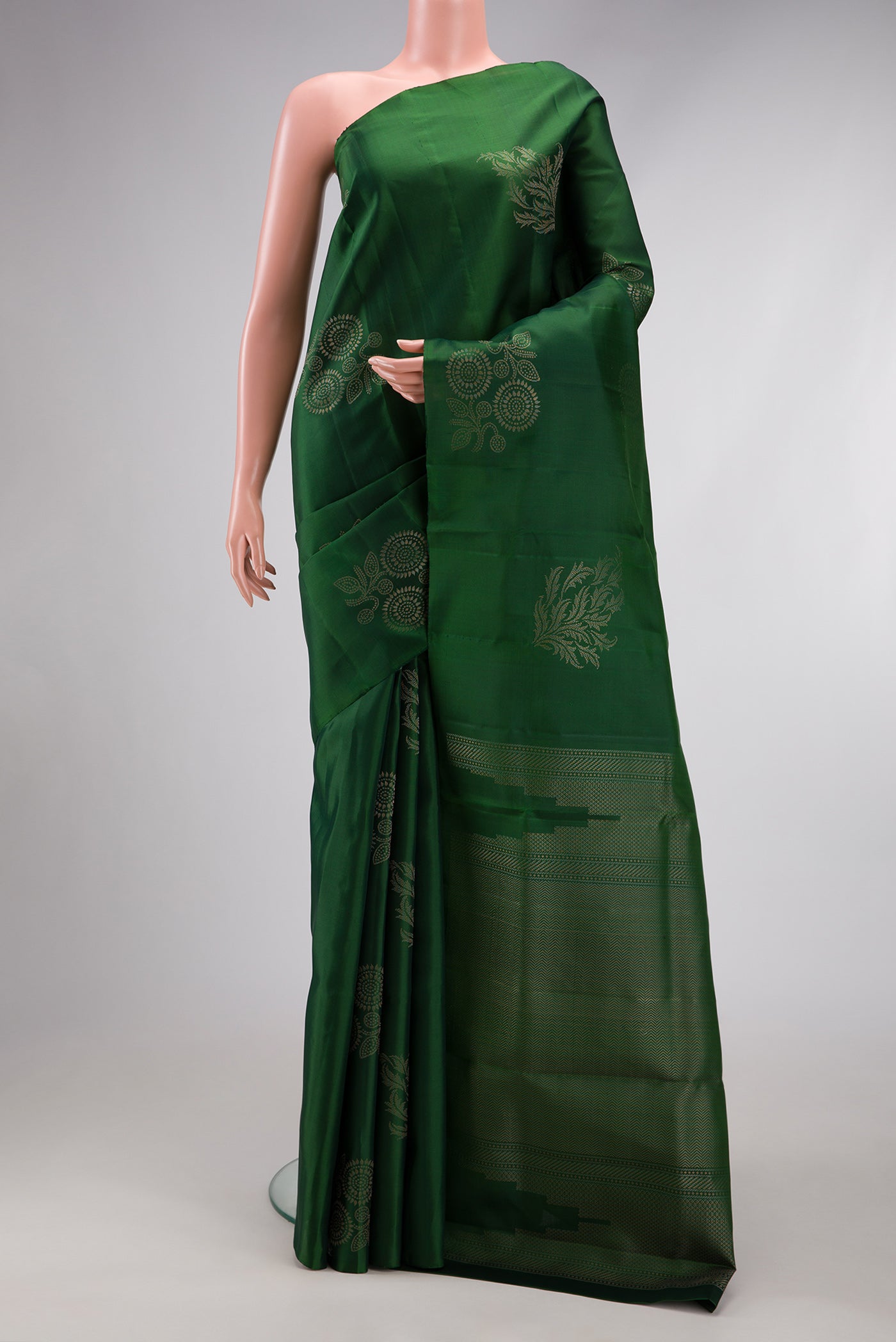 Bottle Green Soft Silk Saree with Zari Butta on the body and Without Border.  displayed on a mannequin