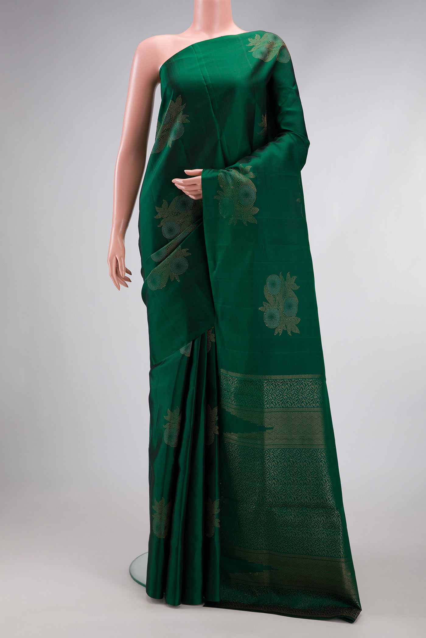 Bottle Green Soft Silk Saree with Zari Butta on the body and Without Border.  displayed on a mannequin