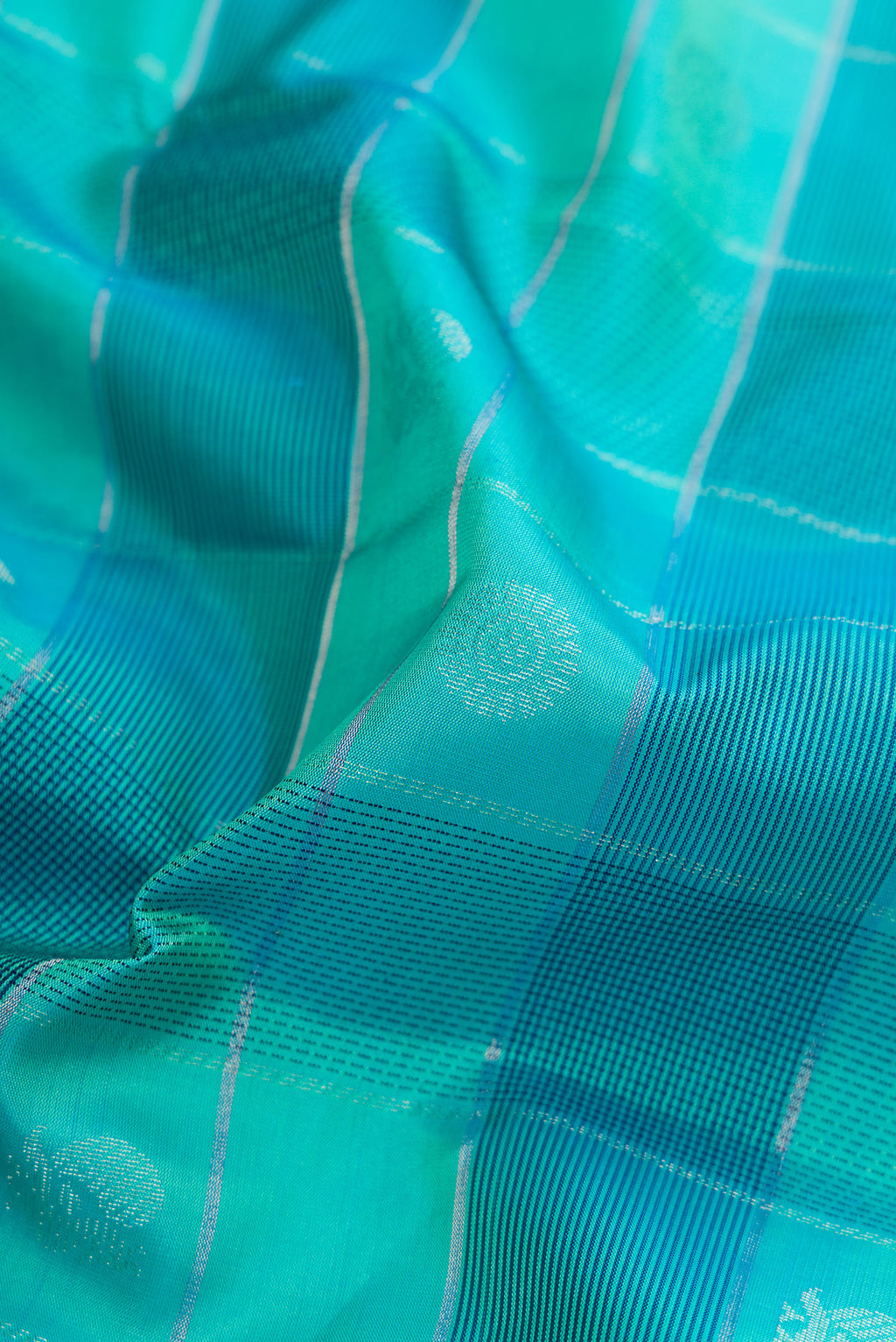 Close up of Sea Green Soft Silk Saree with Checked design on the body and Plain Border.  displaying folds