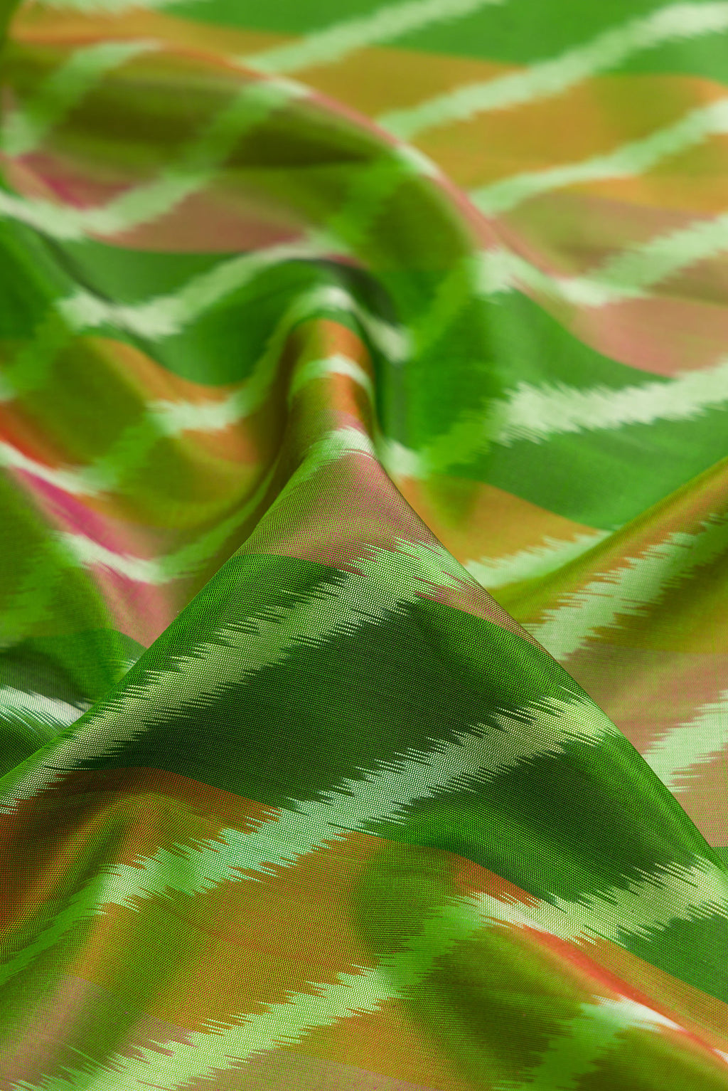 Close up of Green Soft Silk Saree with Ikat design on the body and Zari Border.  displaying folds