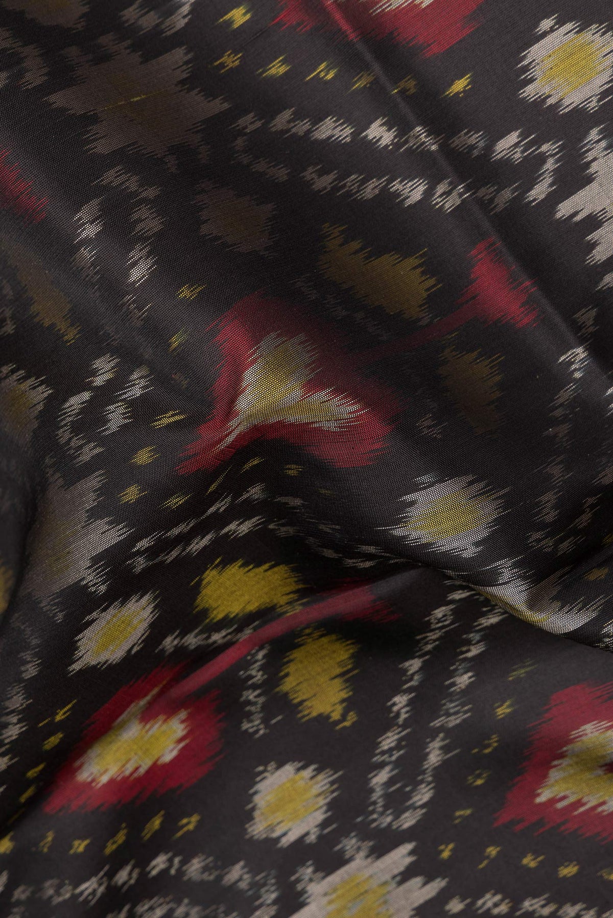 Close up of Pure Silk Black Dual Tone Soft Saree with Ikat Print on the body and Zari Border.  displaying folds