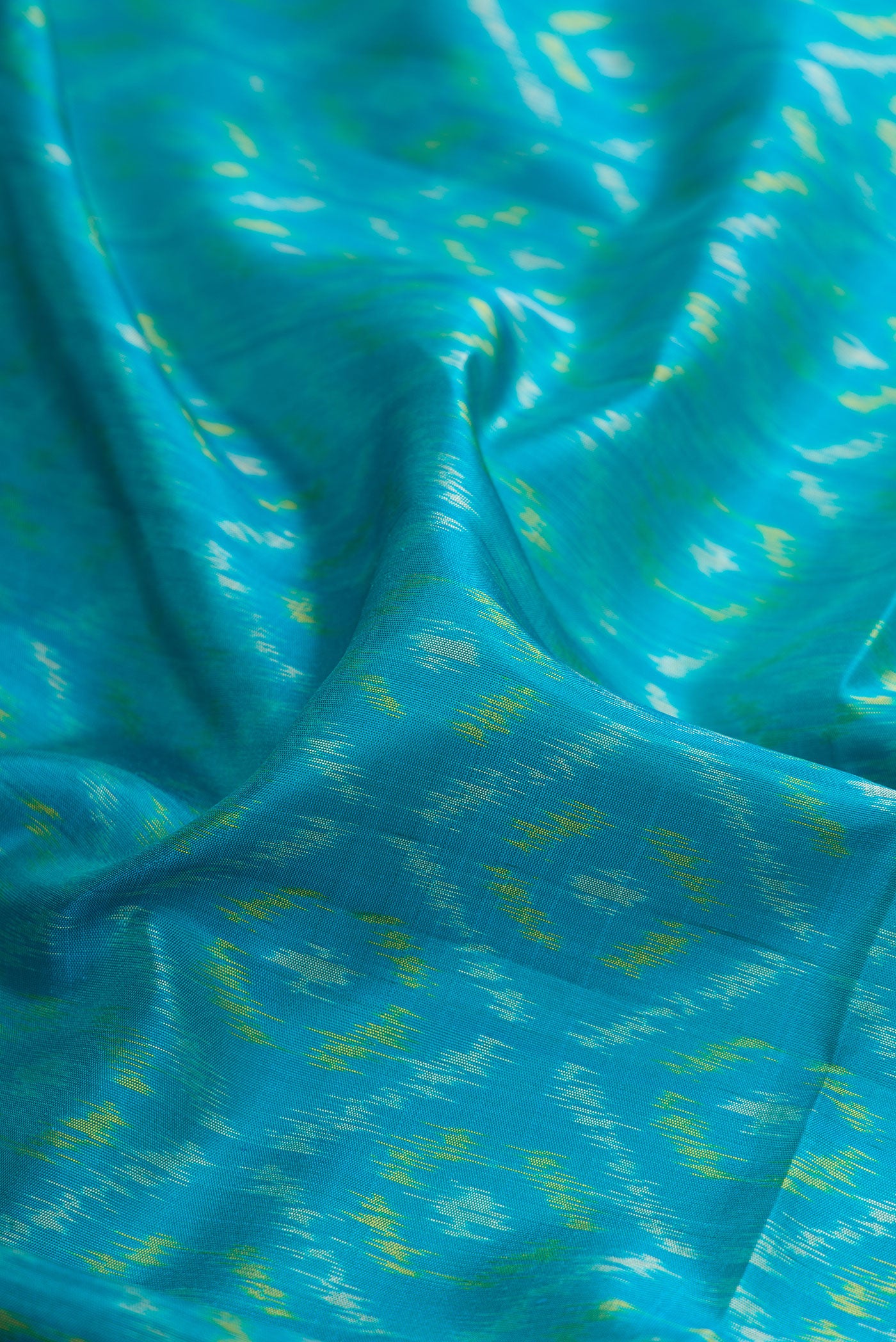Close up of Sky Blue Soft Silk Saree with Ikat Print on the body and Fancy Border.  displaying folds