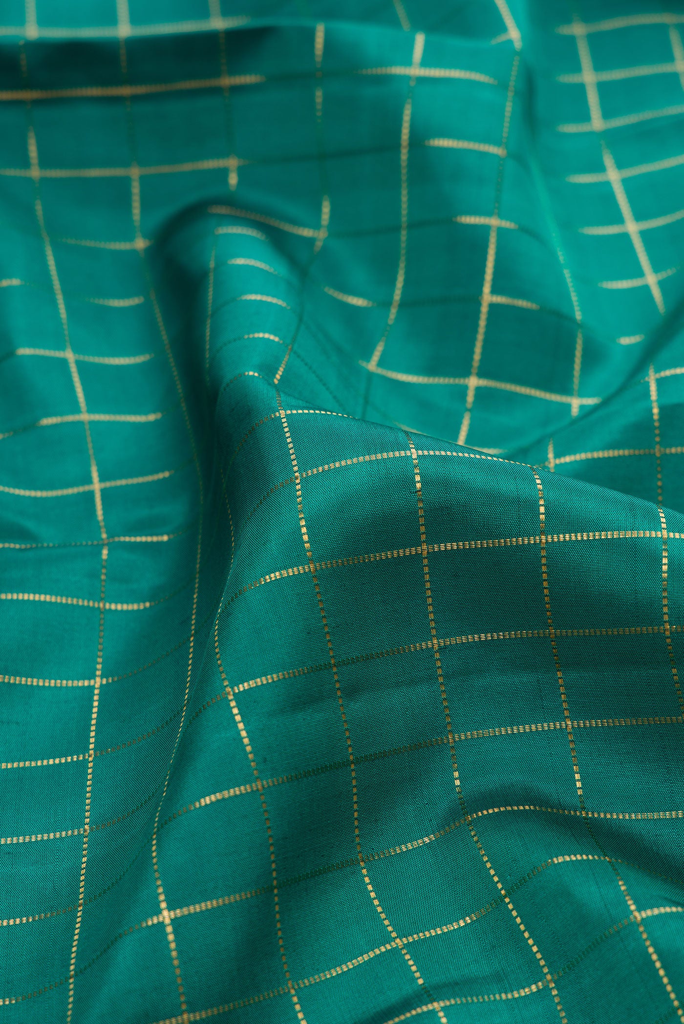 Close up of Green Kanjivaram Silk Saree with Checked design on the body and Zari Border.  displaying folds